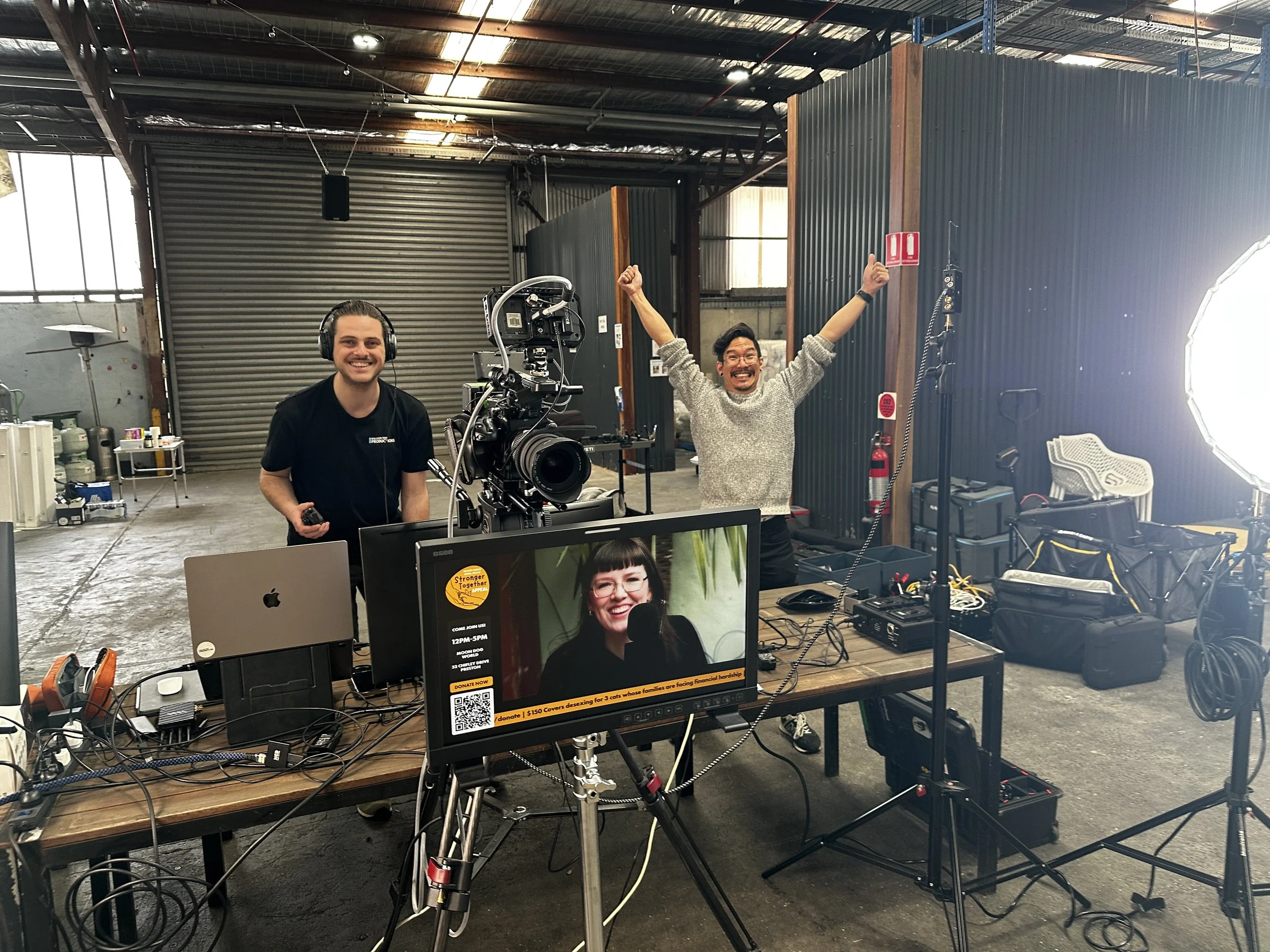 Rob and Ben standing behind the vision mixing desk with Chase on the large monitor