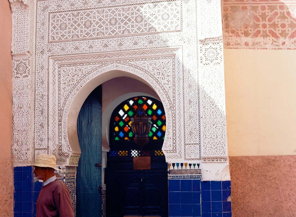 Man in straw hat walking out of doorway with multi-colored glass_Marrakech_web.jpg