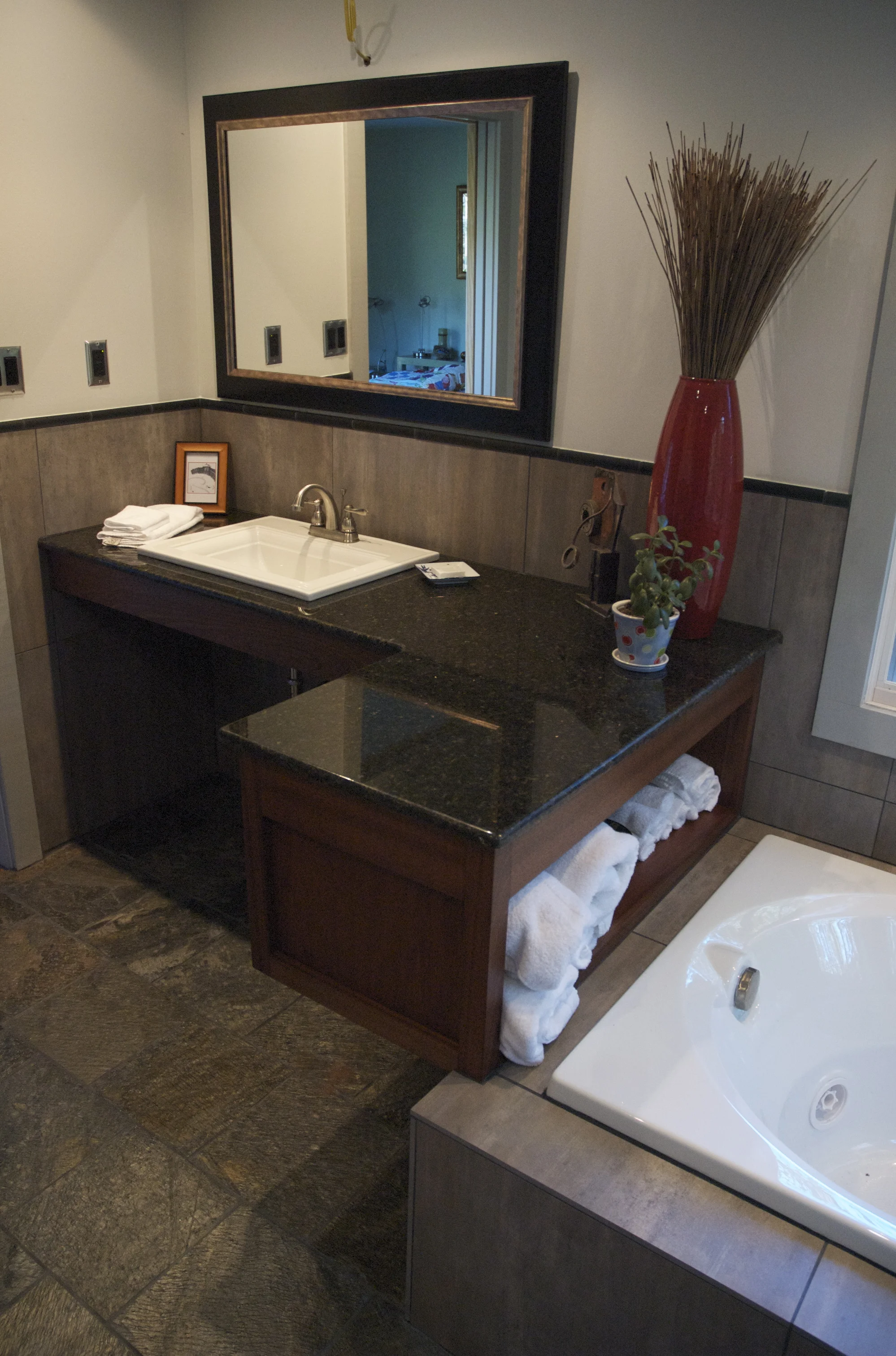 Sapele Vanity. This vanity seems to float. It is lightly supported by the edge of the tub allowing towels to be easily accessible. Sapele cabinet with granite top.