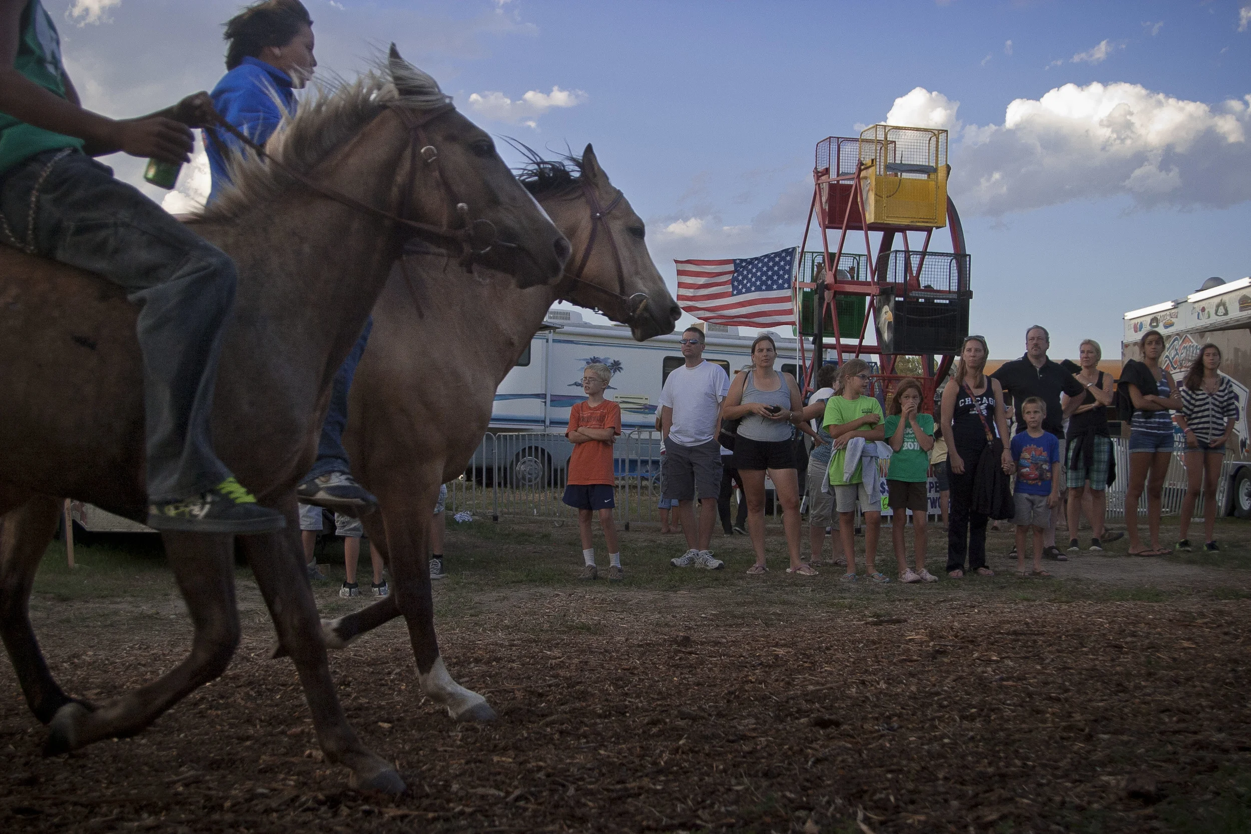 Visitors watch as Oglala Sioux children ride in on their horses for the opening ceremonies at the Pine Ridge Powwow. 