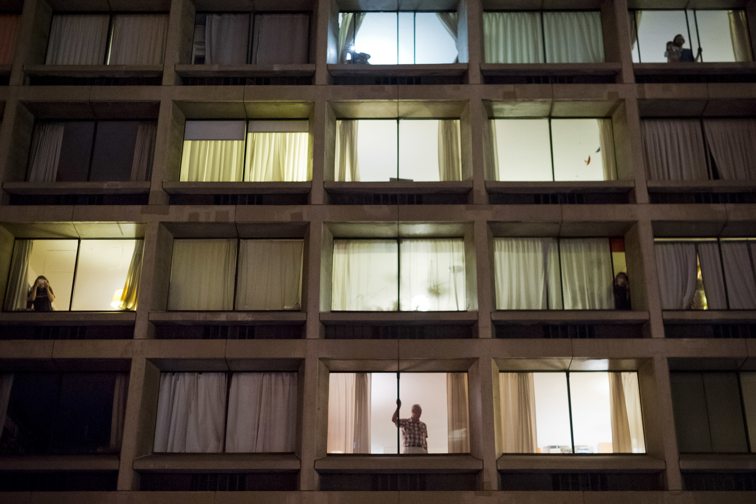  Protest onlookers fill the South-facing windows&nbsp;of an apartment complex on Houston street, 