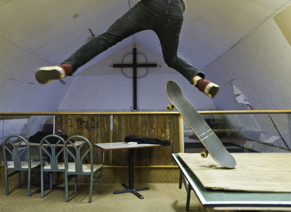 A Skateboarder launches off a ping pong table at the Crossroads Youth Center in Spencerport, NY after worship services. 2012