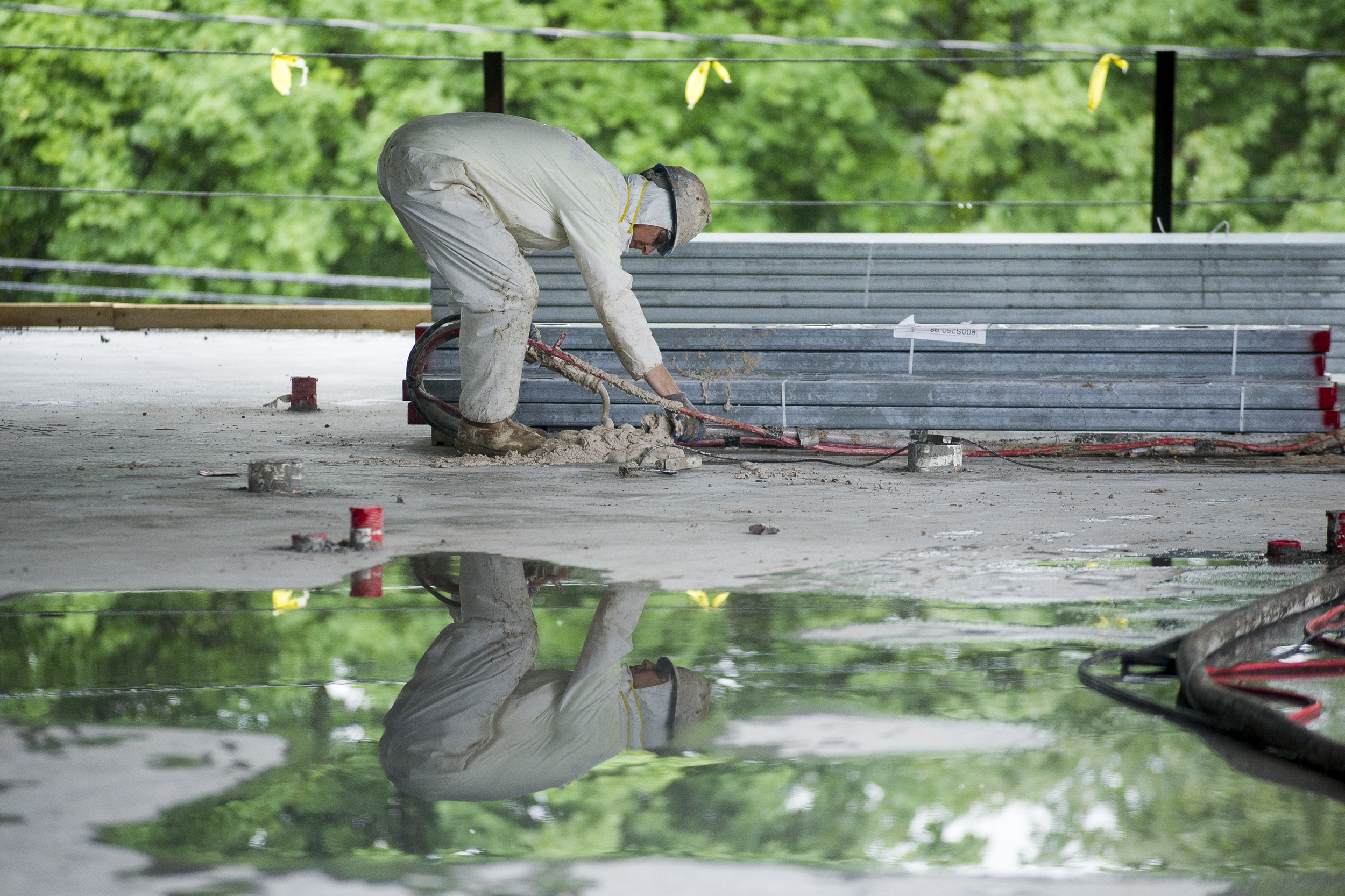  A worker prepares a fireproofing hose. Work continues through the rain at 55-65 Campus Avenue. 