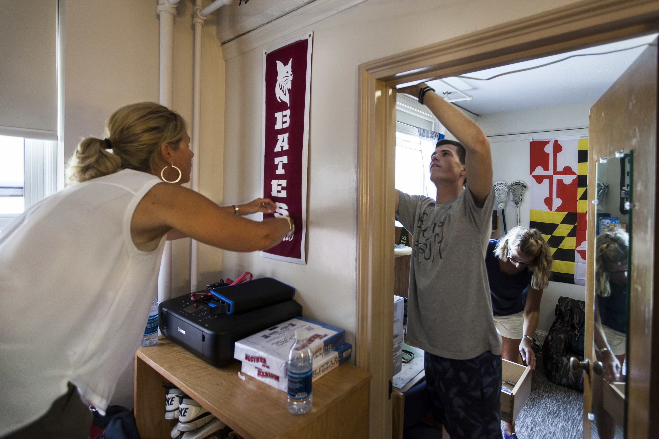  Lisa Legowski hangs a newly purchased Bates banner for her son Justin Legowski '19 of Farmington, Connecticut, while his roommate Eli Nixon '19 of Eliot, Maine, decorates his section of the room on Move In Day. 