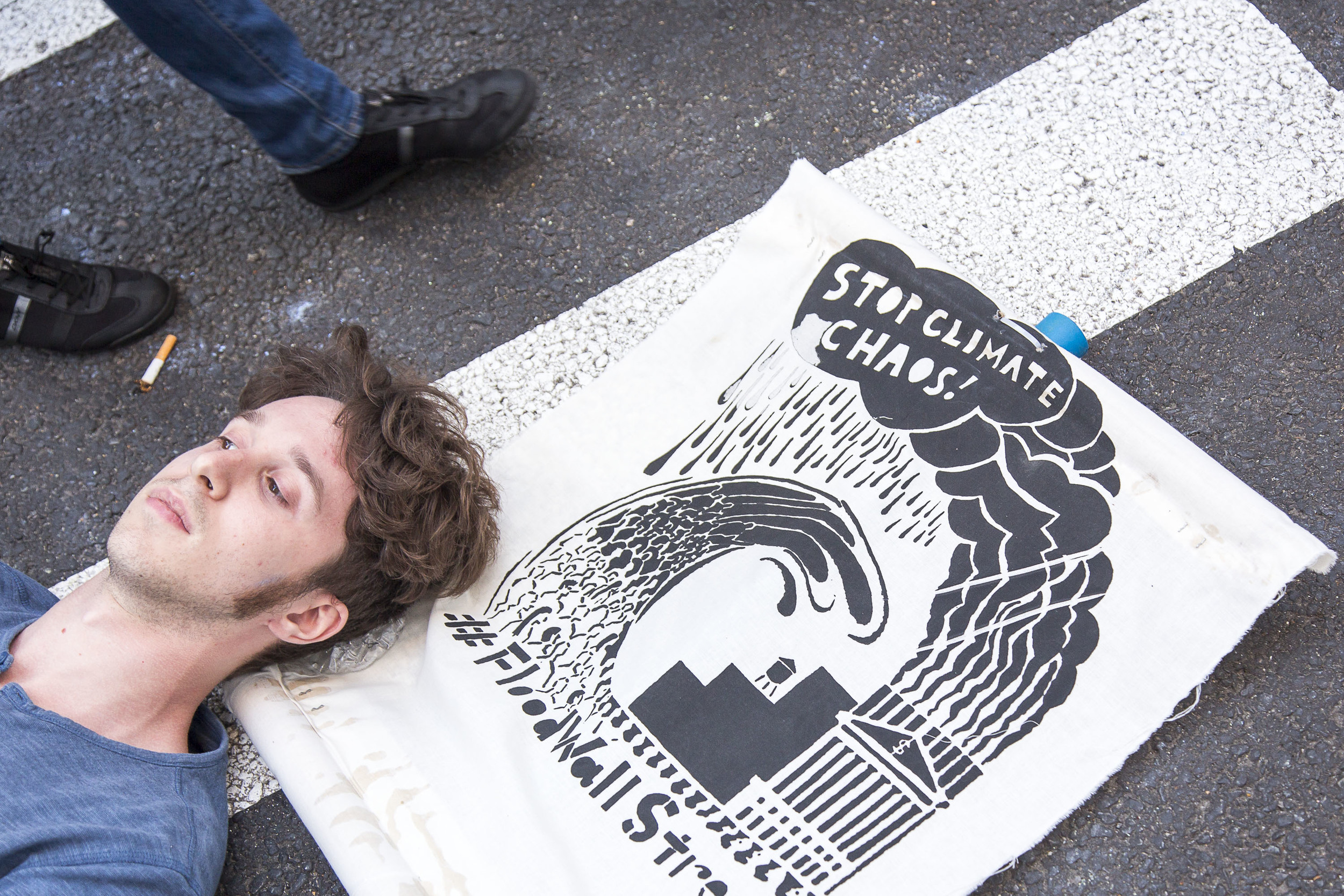 A protestor rests his head on top of a poster on Broadway where it intersects Wall Street.