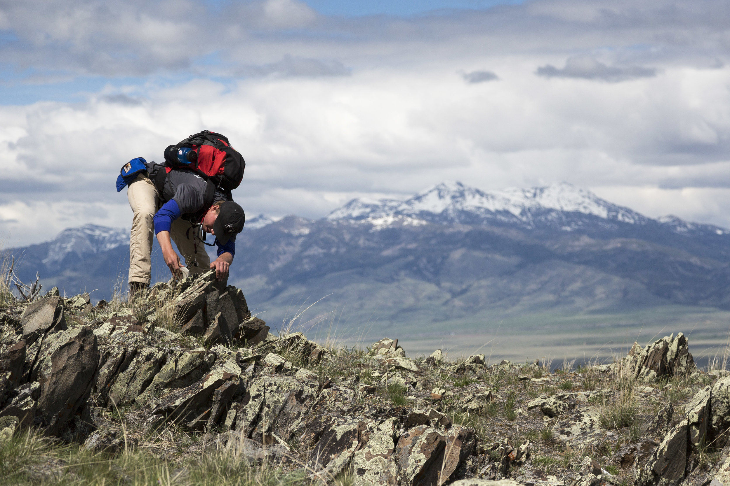  Nick Barker '18 measures the location and angle of different rock formations in the Gravely Mountains, with the Madison Mountains behind him in Ennis, Montana. Barker was enrolled in the Short Term course offering "Geology of the Northern Rockies an