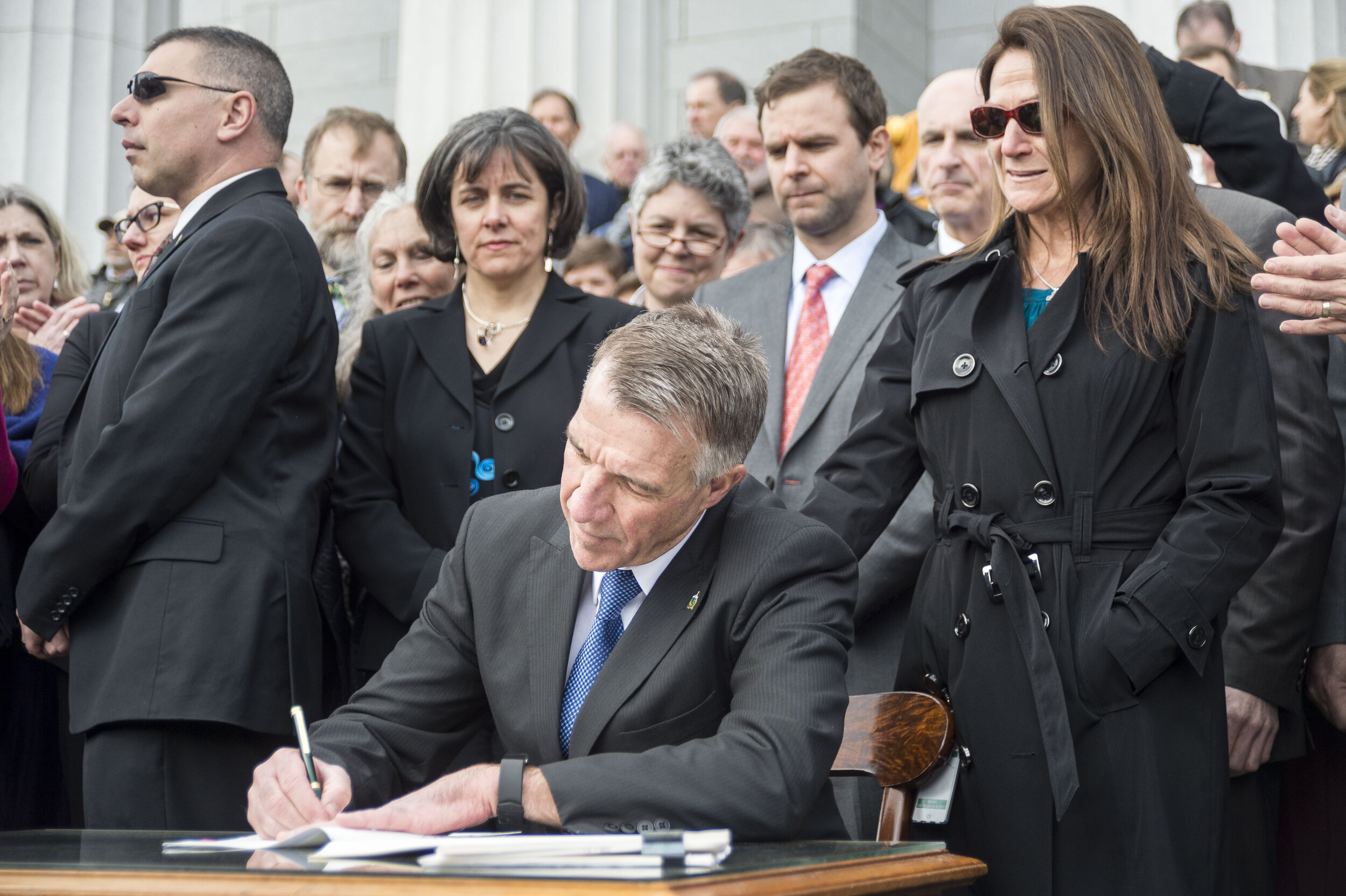  Governor Phil Scott, joined by his wife Diana McTeague Scott, officially signs the bills into law amid a mixture of applause and jeers. Scott signed into law sweeping gun legislation in a public ceremony on the steps of the State House in Montpelier