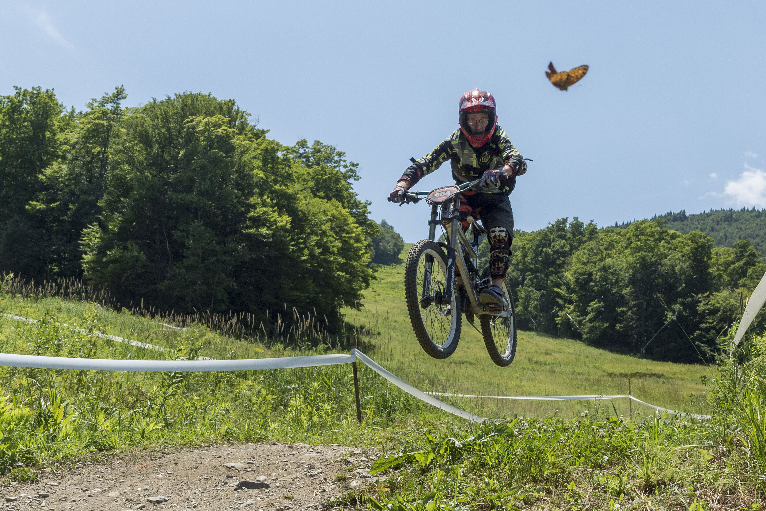  A racer in the Eastern States Cup Sugarbush Showdown mountain biking event looks at a passing butterfly while completing a jump in Warren, VT on Saturday, July 15th 2018. 