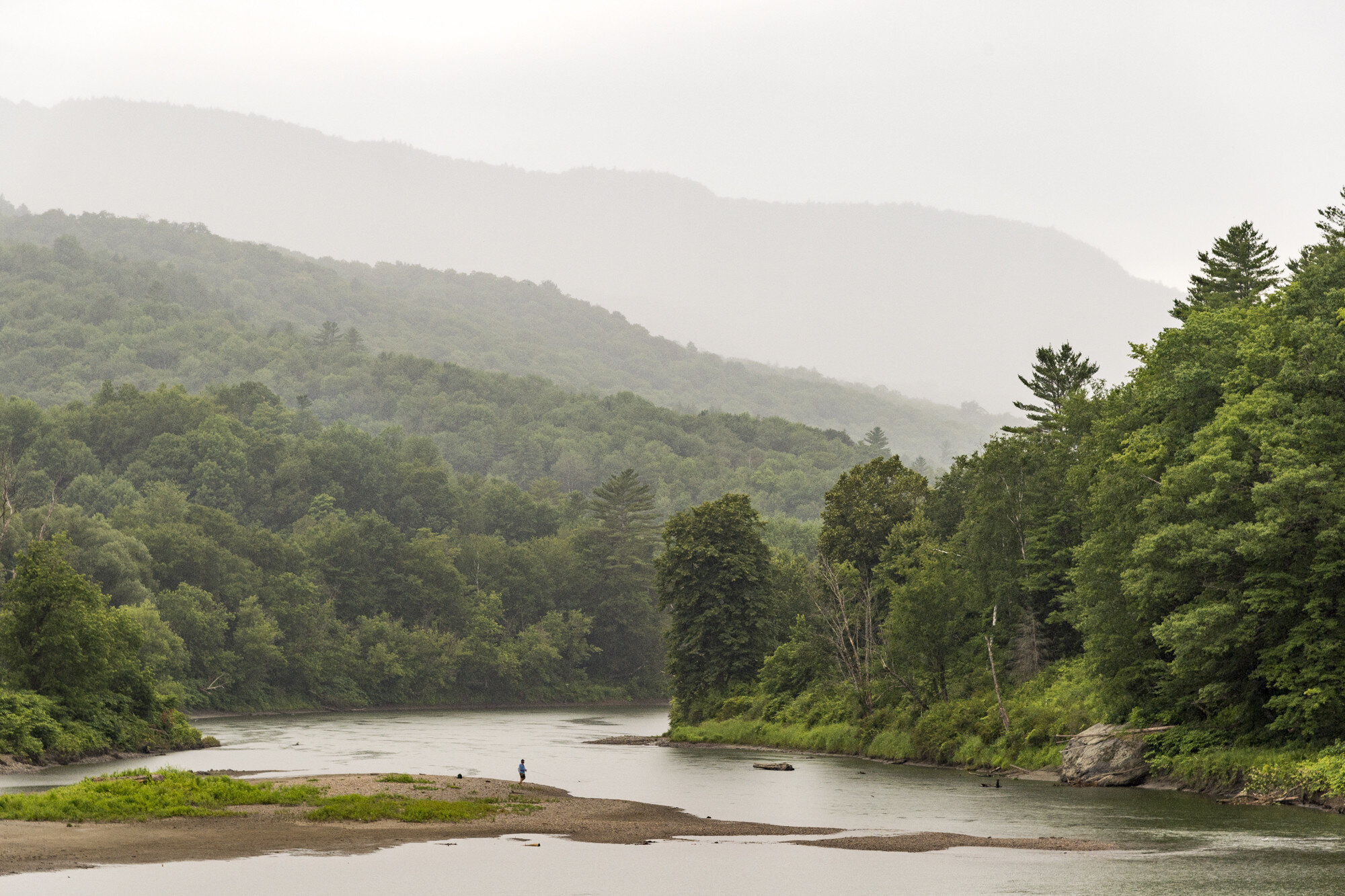  A lone fisherman carries on through a rain shower on Tuesday, July 16th 2019 at the Bolton Falls recreation area in Waterbury, VT.  