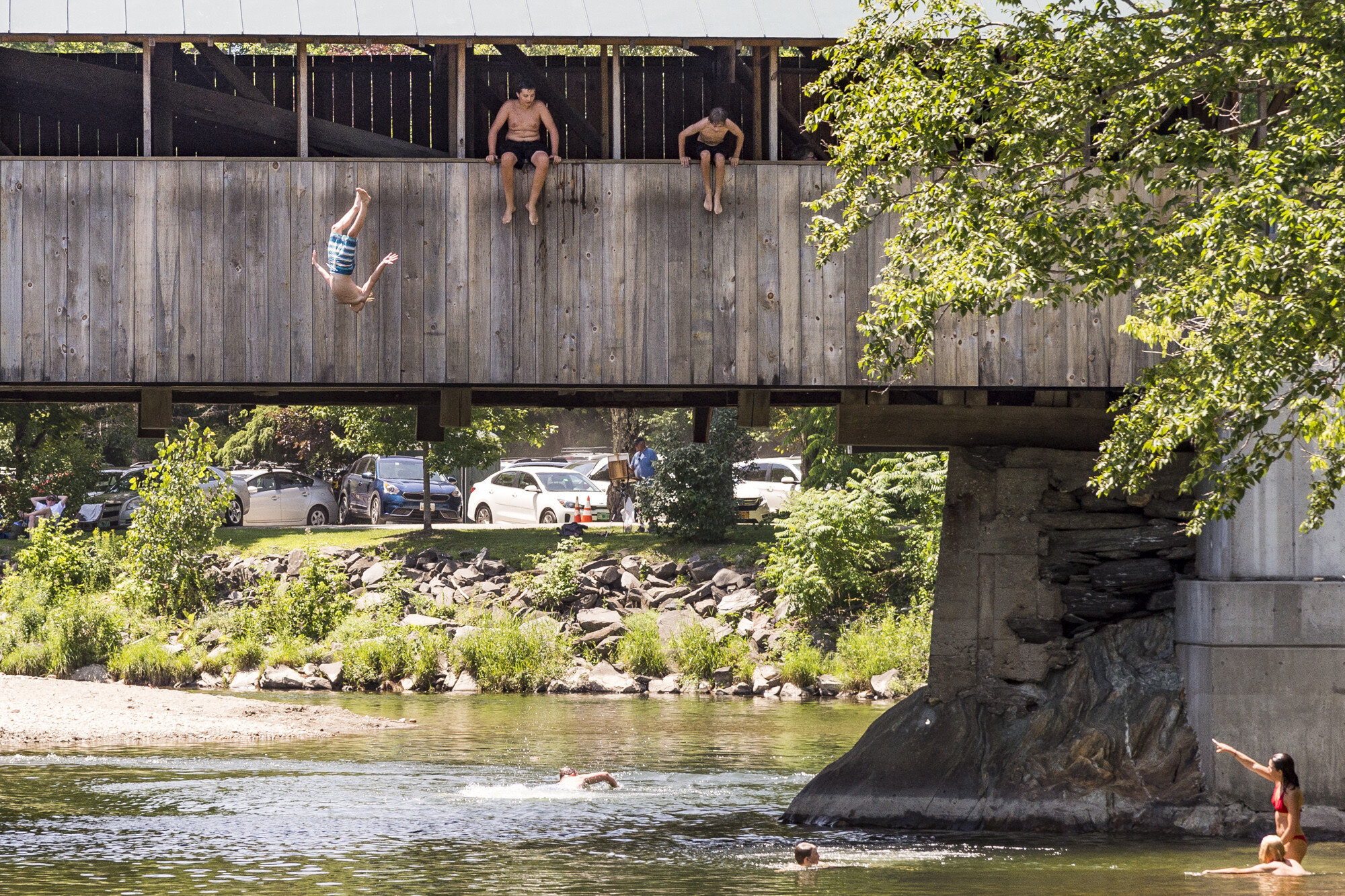  Swimmers looking to escape the weekend heat take turns plunging into the Mad River from Big Eddy Covered Bridge in Waitsfield, VT on Saturday, July 20th 2019. 