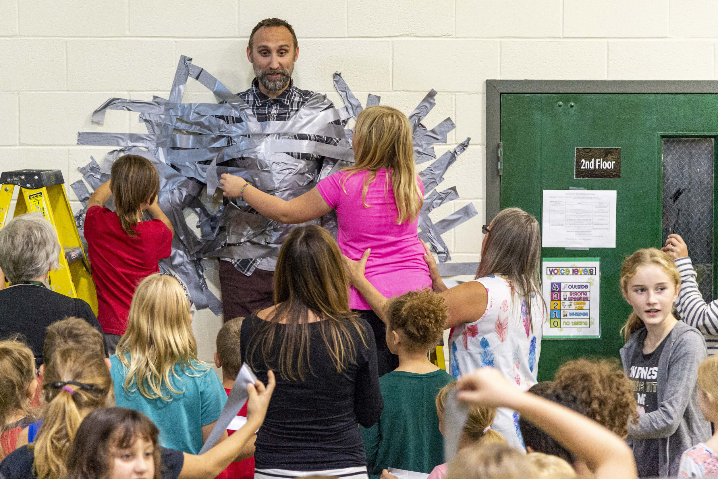  Berlin, VT Elementary School students take turns in helping to tape their Principal Aaron Boynton to the wall of the gymnasium on Thursday, September 26th 2019. The activity was a reward for good student conduct as part of the school’s Positive Beha