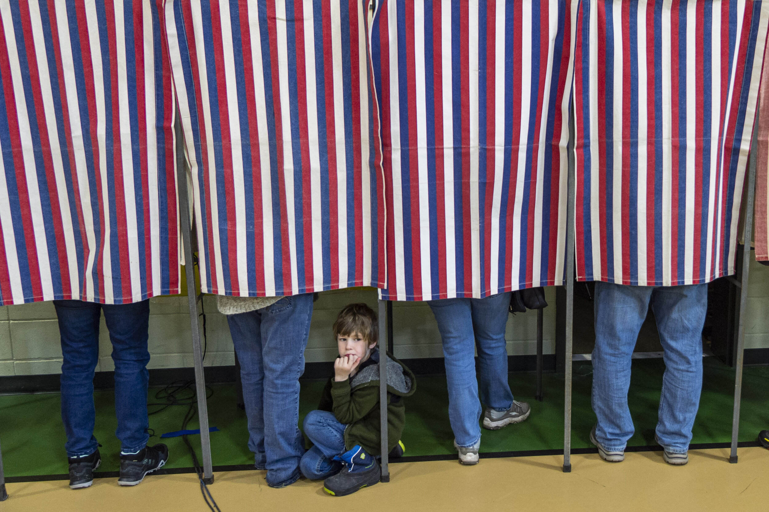  Eli Buschey, 6, joining his grandmother Kathryn as she casts her ballot, peeks out from the voting booth at Berlin Elementary School on “Super” Tuesday, March 3rd 2020. 