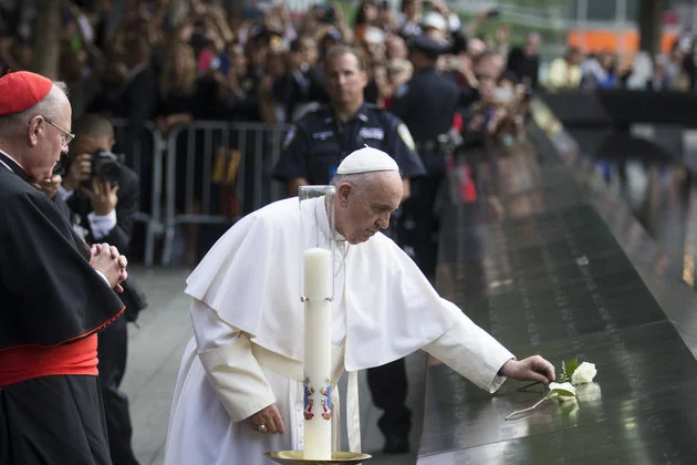 AP/John Minchillo- Pope Francis places a white rose at the South Pool of the 9/11 Memorial in downtown Manhattan, Friday, Sept. 25, 2015, in New York. 