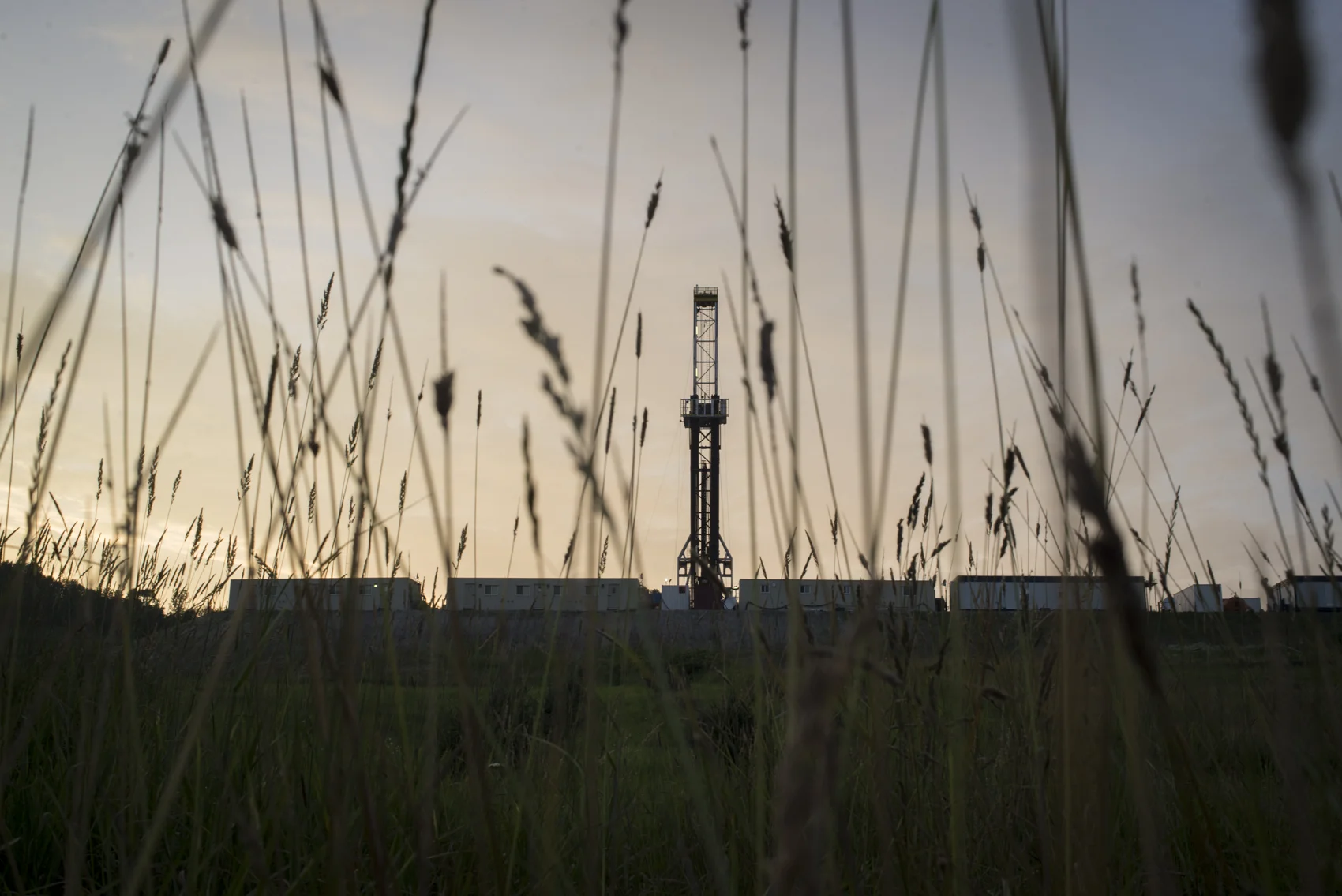 A gas rig juts into the air above a Susquehanna County field at sunset.