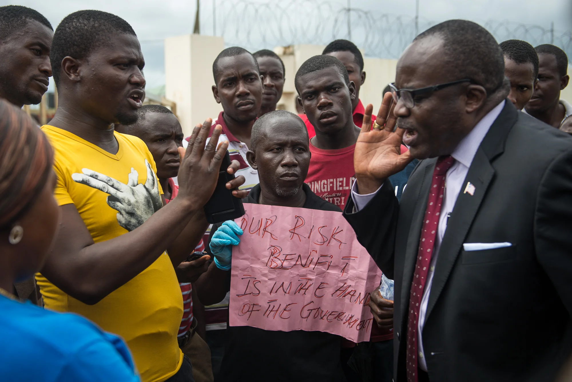 Benedict Sannoh, Liberia's Minister of Justice (right), argues with protesting health care workers on Wednesday, July 1 outside the Ministry of Health in Congo Town, Liberia. The workers claim that the government has not paid them a promised risk benefit bonus for the hazards of working in Ebola treatment facilities. 