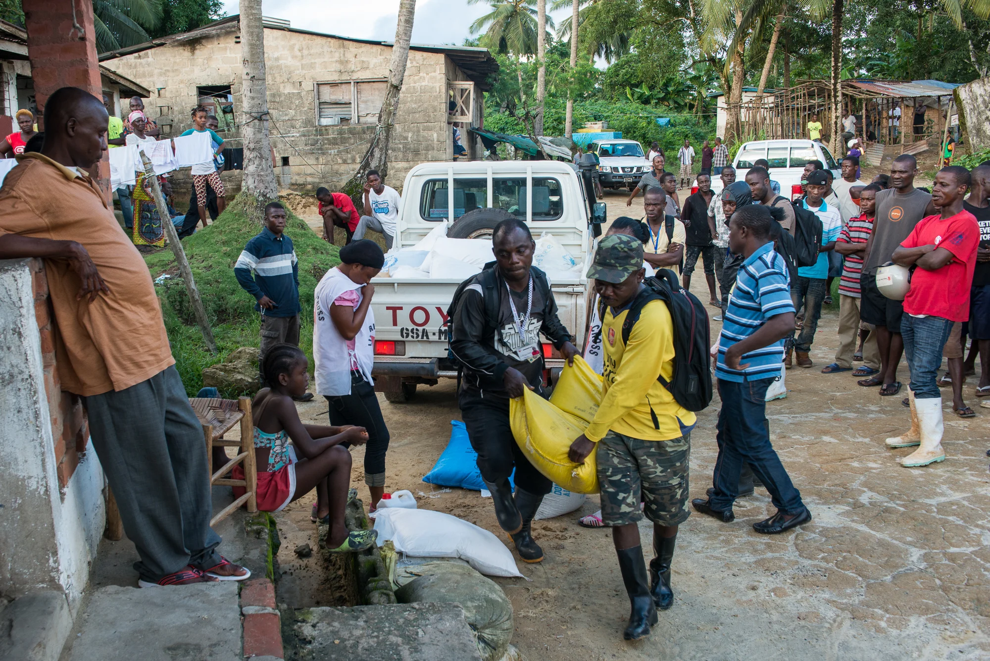 Liberian Red Cross workers deliver food aid on Tuesday, June 30 to the home of James S. Memaigar (left), the father of 17-year-old Abraham Memaigar, whose corpse tested positive for Ebola in Liberia two days earlier. Memaigar's family was quarantined in their home. 