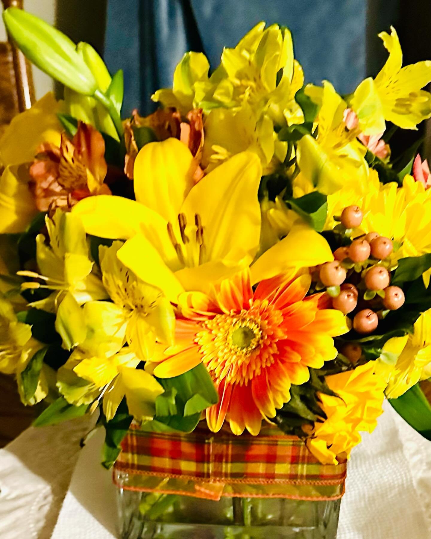 Seasonal and Sunny Fall Arrangement in a Plaid Ribbon Trimmed Vase.
