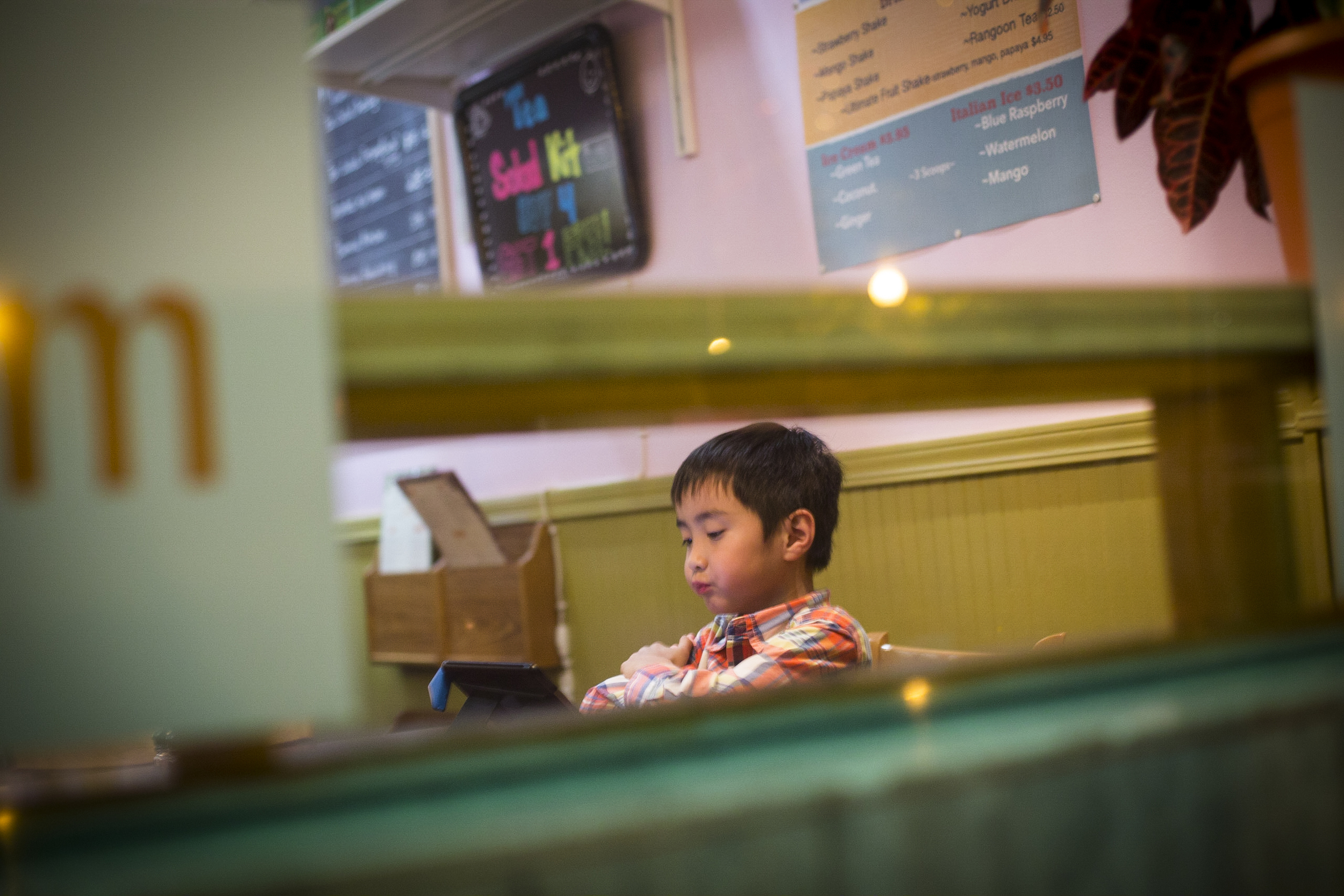  Henry Kyaw, 7. When the restaurant is less busy, Henry, the son of the owner of Yoma, can take the seat in the restaurant and play games on his tablet. By Ann Wang 