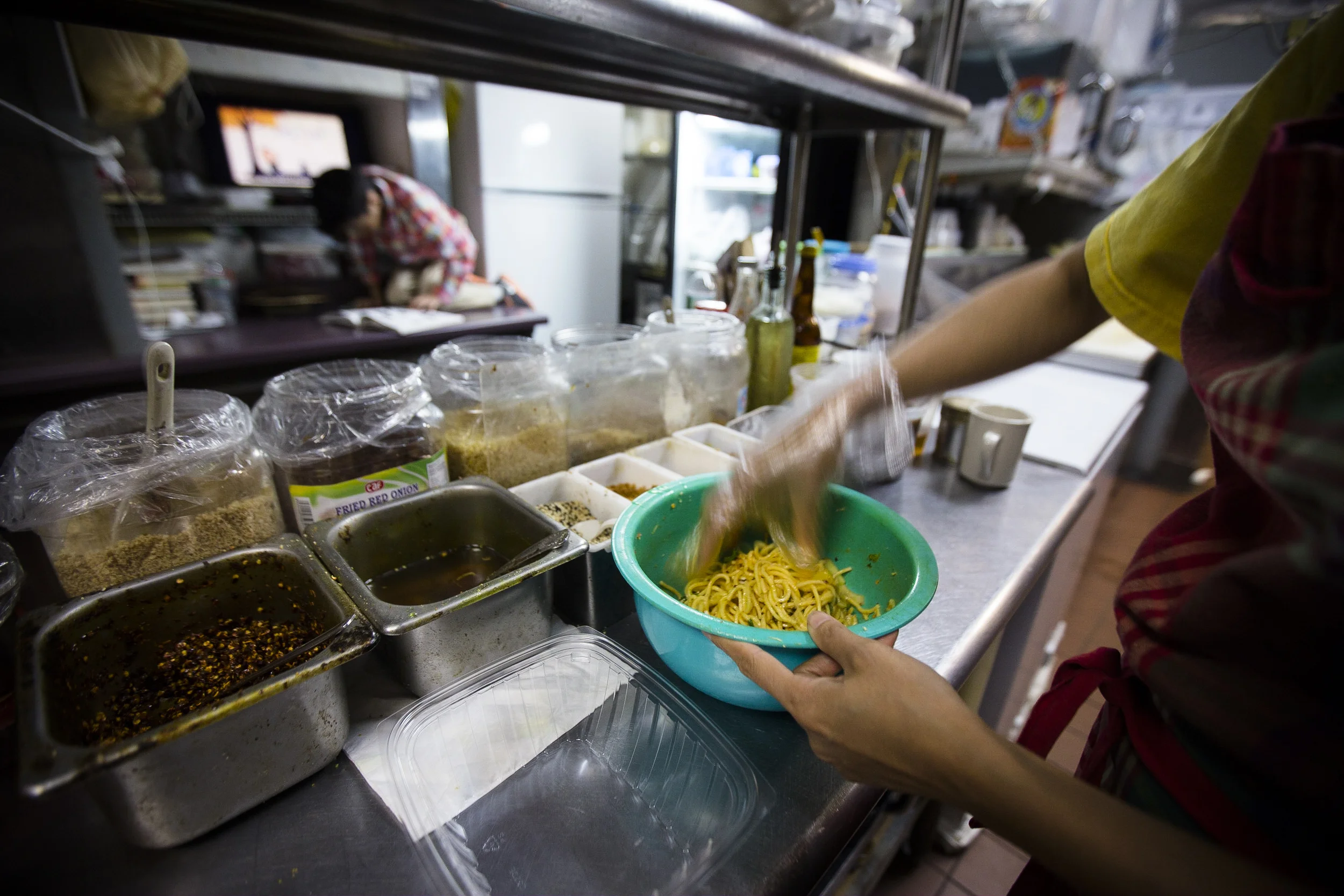  Thawdar Kway is mixing the noodles with spices to make Happy Noodle. By Ann Wang 