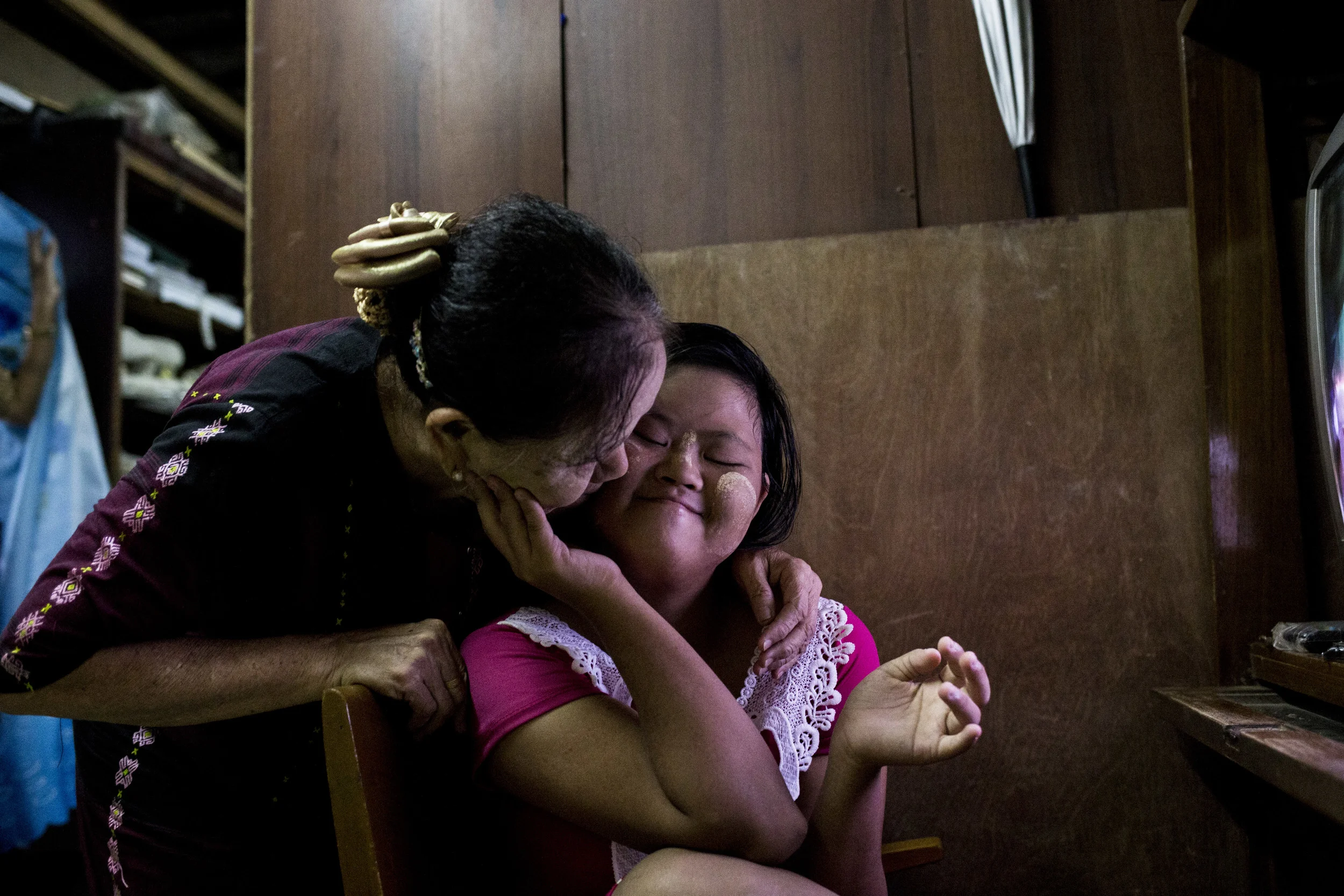 Theint Theint Thu’s mother kissing her on the check. The family never thought about giving her up because she has down syndrome, instead they focus on what to do to make her happy everyday. Photo by Ann Wang