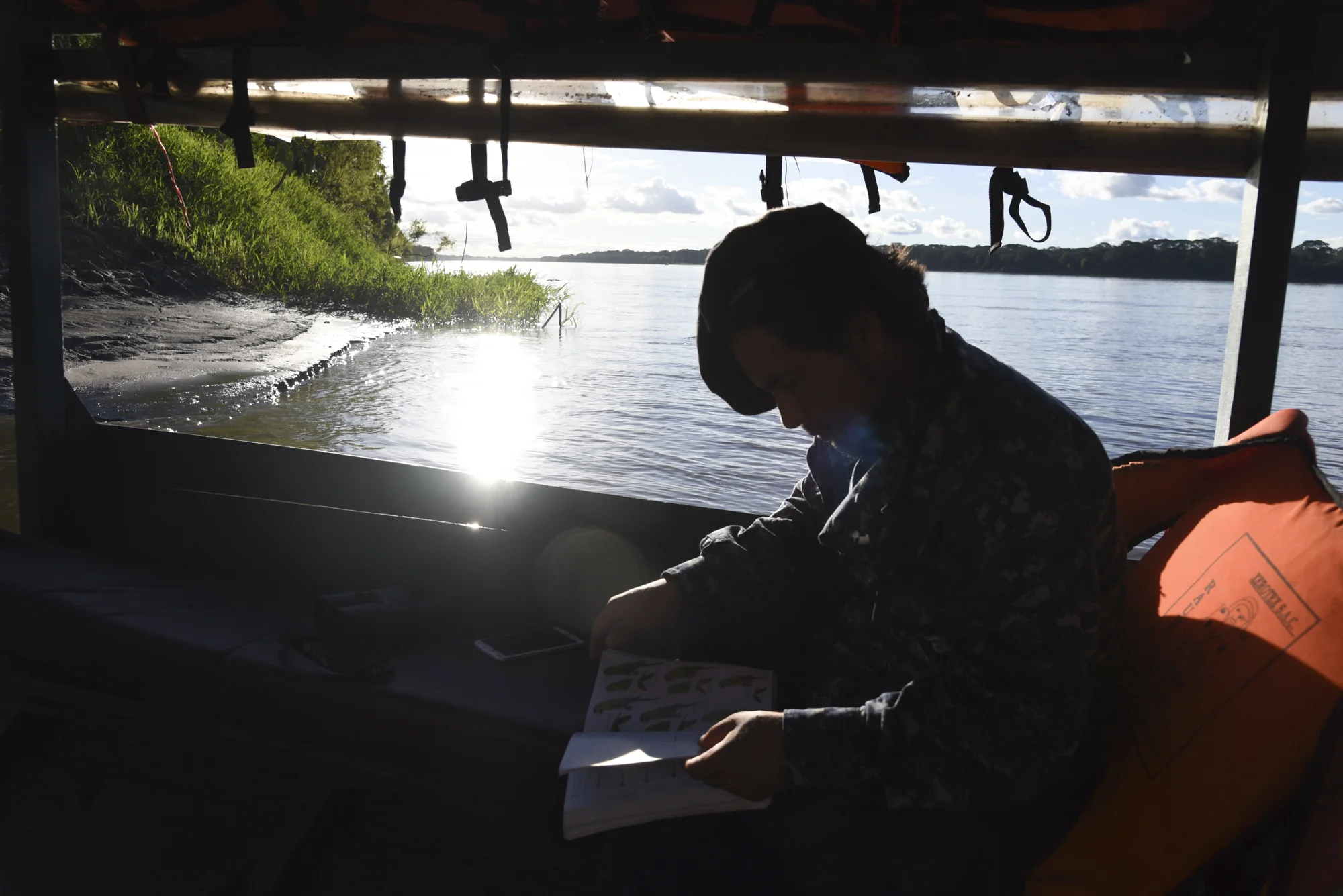  After registering his Global Big Day results, Yohamir continues to study his "Birds of Peru" book and search for more birds during the boat ride back to camp. 