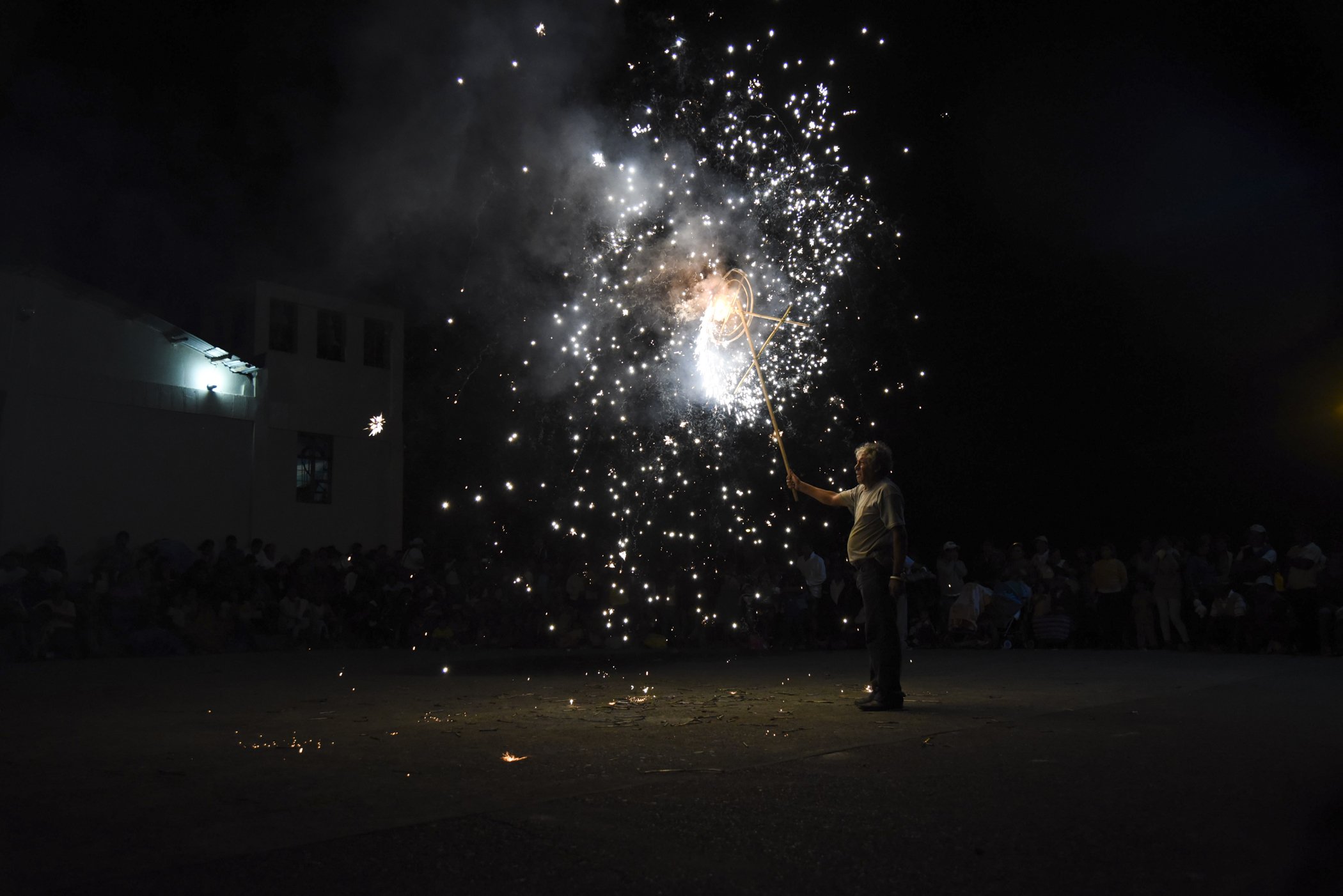  A man ignites a firework display for a crowd of onlookers during a town anniversary celebration in Pillcopata, Peru.  