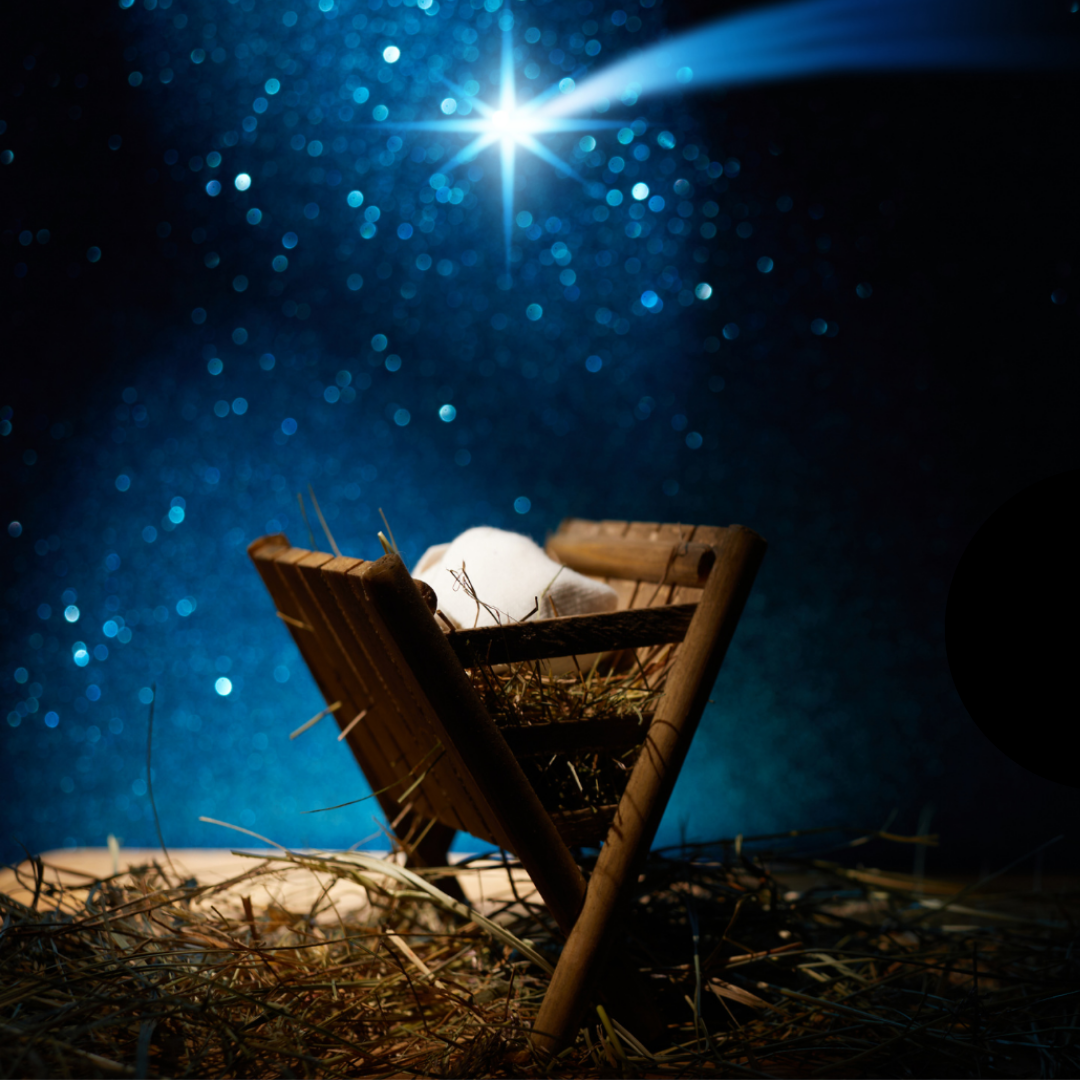 A manger with a blanket inside, standing in straw or hay, with a bright star in the sky