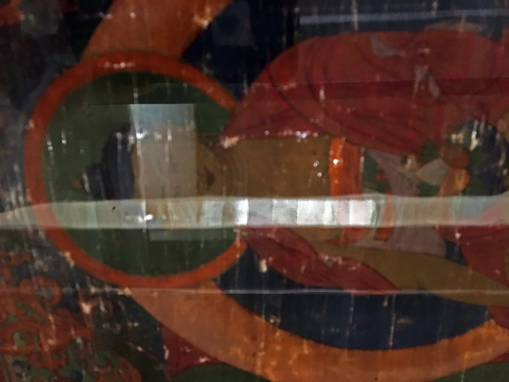 Painted side of Thangka through the table glass.