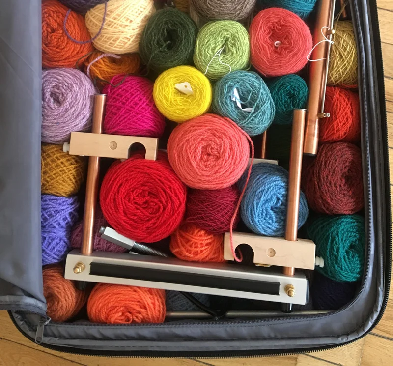 This is a 12-inch Little Guy Mirrix pulled into two pieces. Notice the clips are turned sideways. The other half was in some other part of the bag. I like to pack the looms with yarn whenever possible. You can see a warp extender peeking out below the loom.