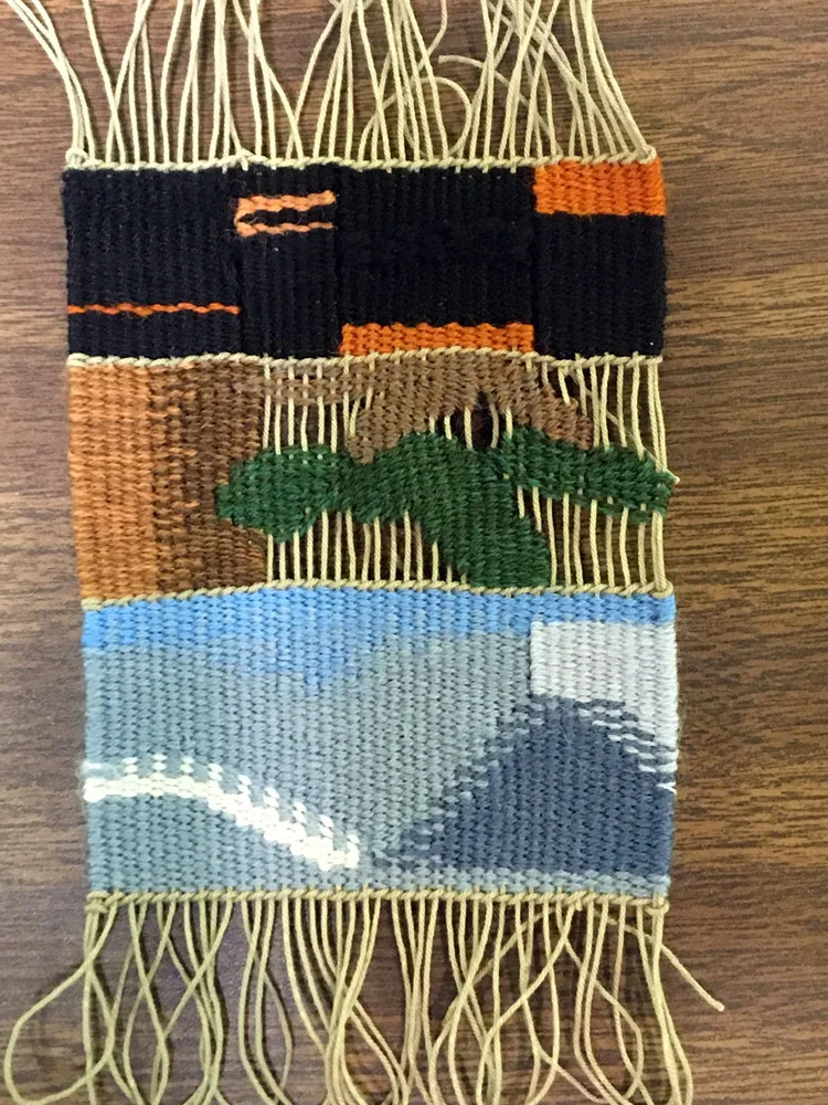 Liz wove a piece each day on the same loom. She wanted to respond to the environment and day one at the bottom was about clouds, the center one was woven after a long hike to Emmaline Lake when she was tired so she included the exposed warps in her interpretation of a tree to reflect that, and day 3 was about all the old burned trees around campus. She was thinking about the glossy black wood and reflecting that with a couple different fibers--both cotton and wool--which reflected the light differently (unfortunately difficult to see in this photo).