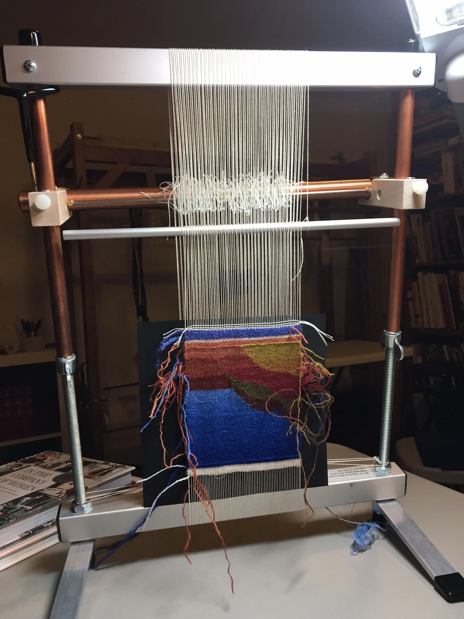 Back of the loom showing the advanced piece upside down and the warping bar a little more than halfway up the back.