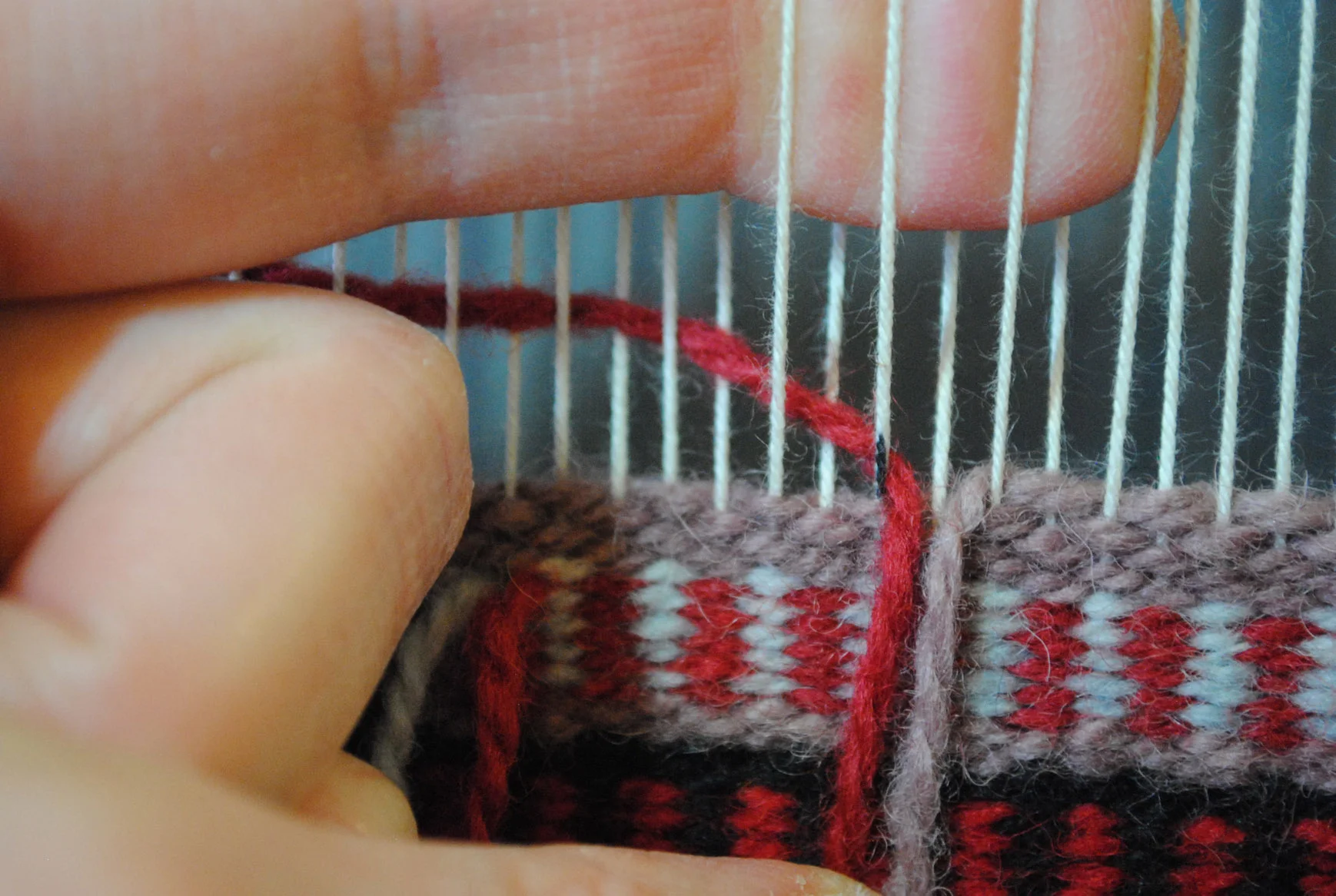 The warp that confuses people is down in this photo--between the red and mauve yarns. My finger is indicating the open shed.