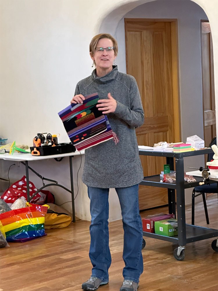 Rebecca Mezoff teaching tapestry weaving in Taos holding a tapestry sampler