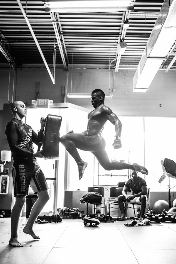 Philip Hawes executing a beautiful flying knee while Stefan Struve holds the pad for him and Anthony Johnson looks on.