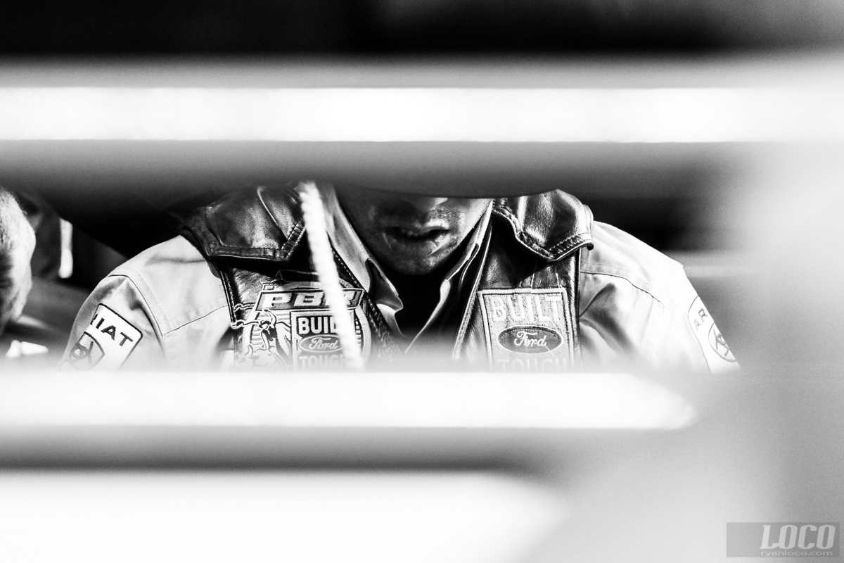 A bull rider sits upon his bull and prepares himself in the chute, waiting until he feels the proper moment to give the signal and open the cage.
