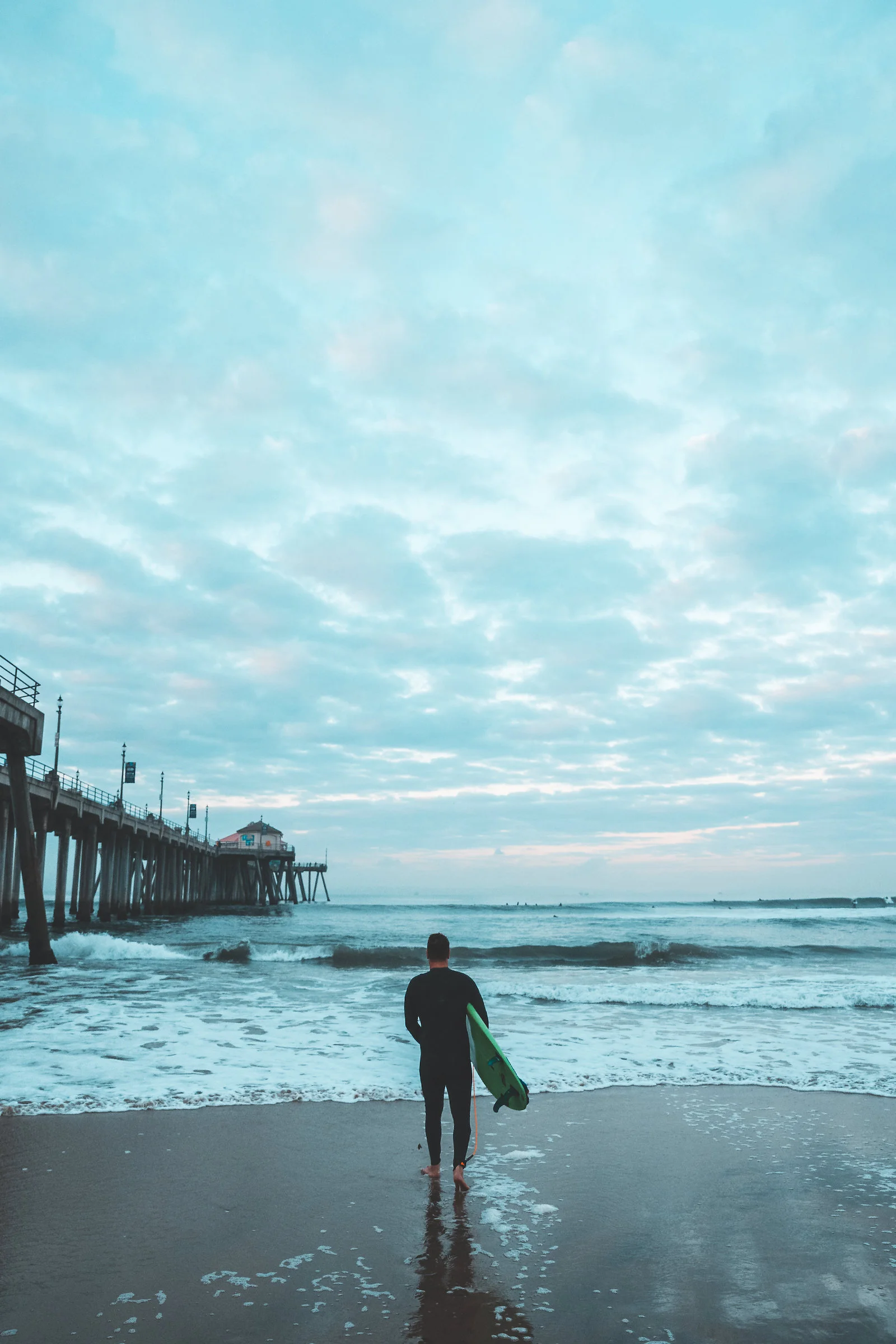 A surfer going out for a sunrise session in Huntington Beach, CA.