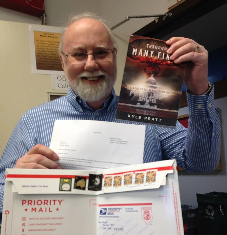 Kyle Pratt holds a copy of his book, Through Many Fires, sent to him for an autograph
