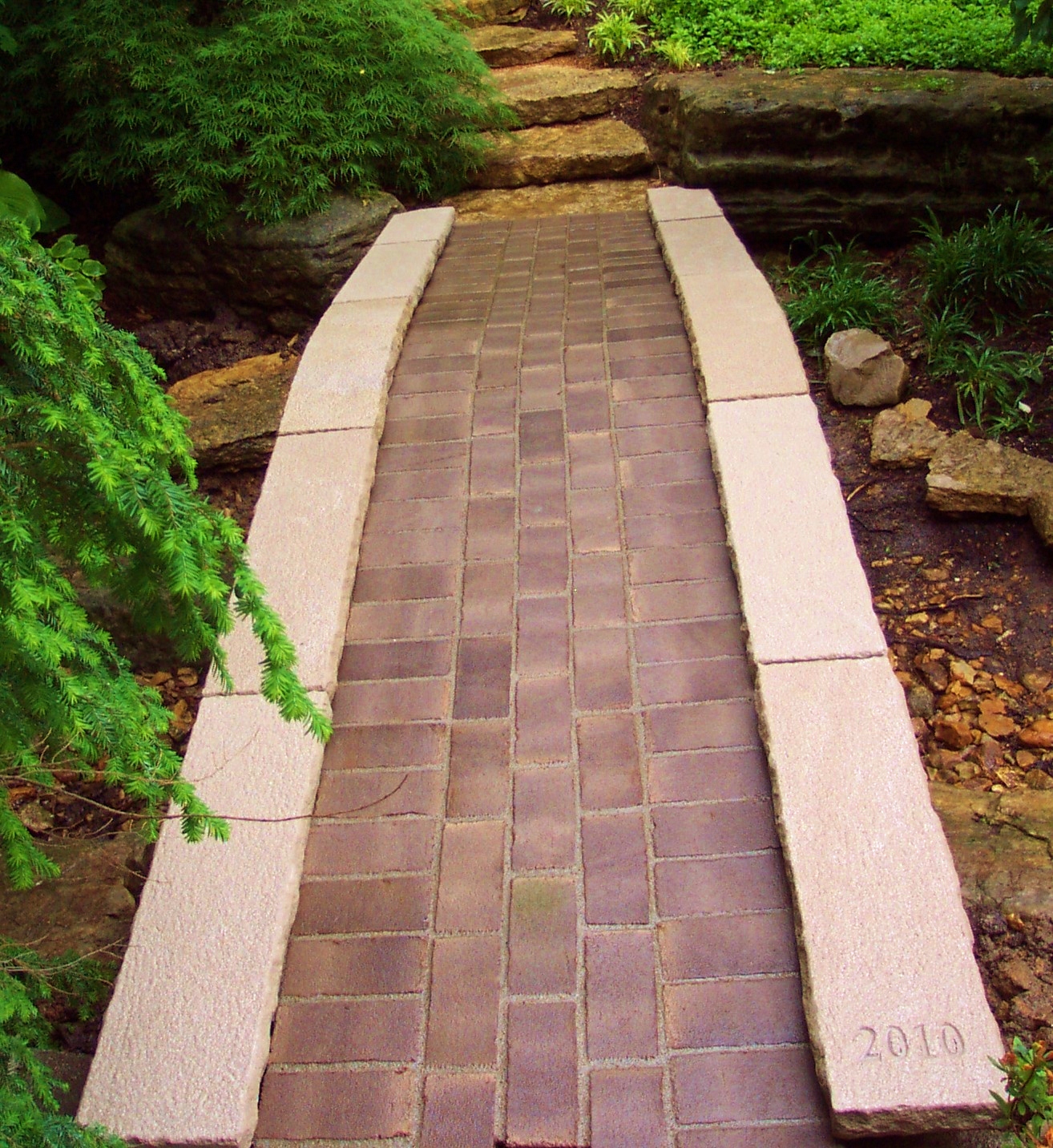Stone arch bridge with a brick path inlay.  Stone Works  Lee Lindsey St. Louis, MO