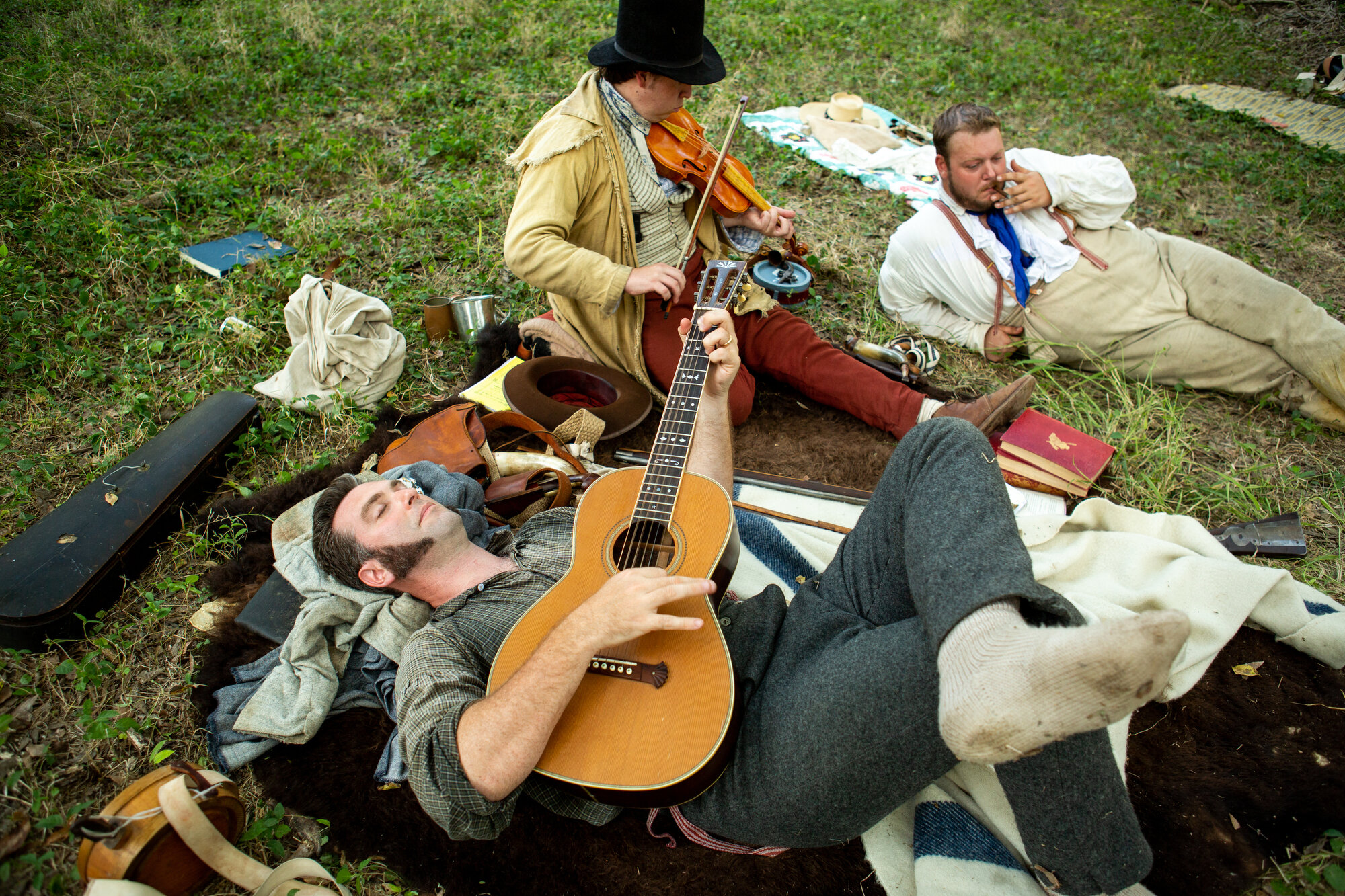  Andrew Gray, left, Jameson Moore, middle, and Kevin Malcolm lie in the grass and entertain themselves in their Texian encampment set up in Goliad, Texas during a reenactment and living history event on Saturday, Sept. 7, 2019.  