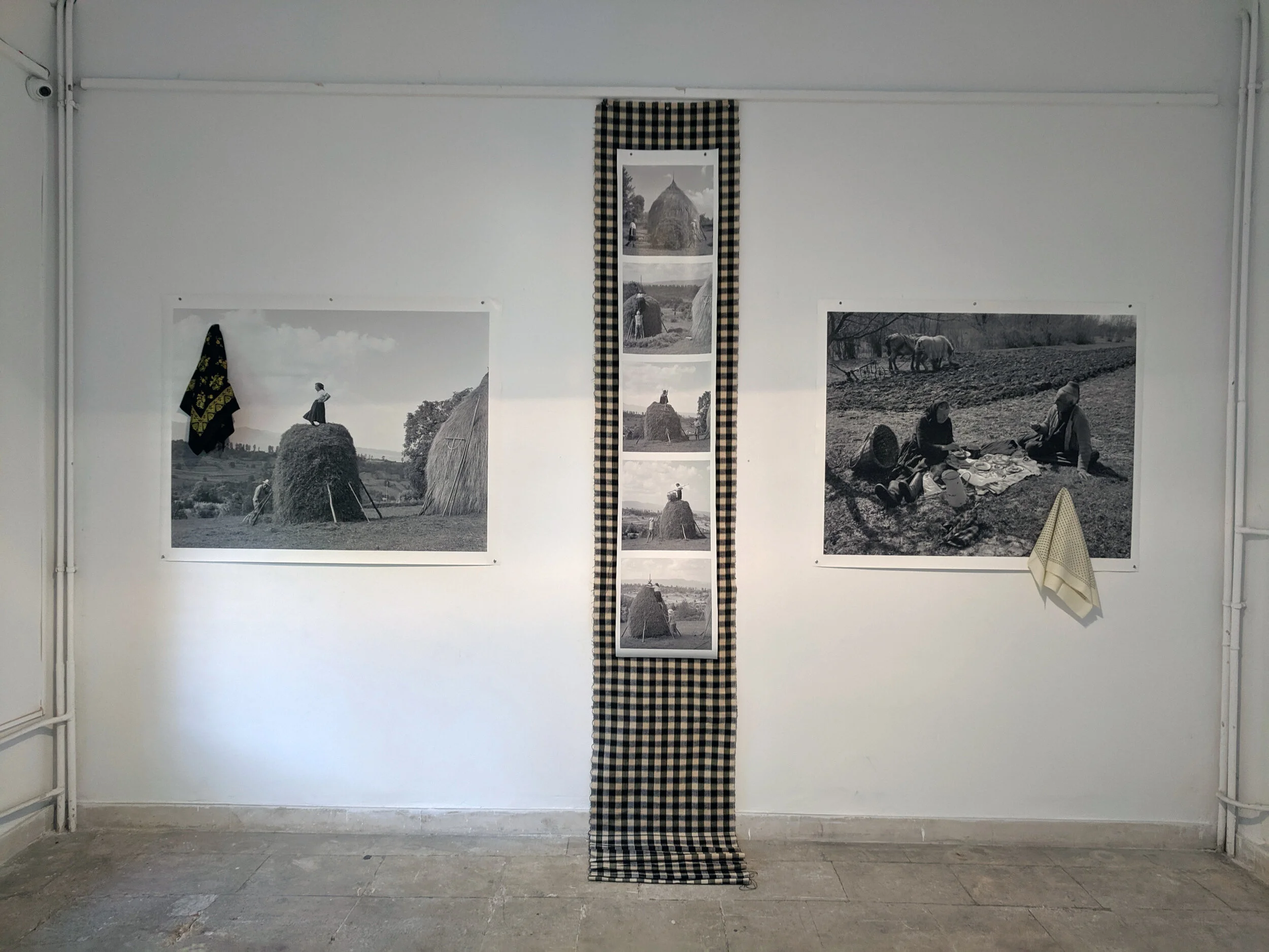 Installation of exhibition. The vertical center piece is a bolt of woolen woven fabric Matusa made for future tote bags. These checkered totes are ubiquitous in the Maramures region.