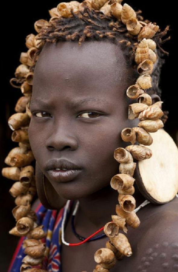 Portrait of Mursi Girl, Omo Valley, Ethiopia by Peter Adams This oversized print hangs in the entryway of our storefront. Each time we enter we are inspired by the wisdom and resilience in her eyes.