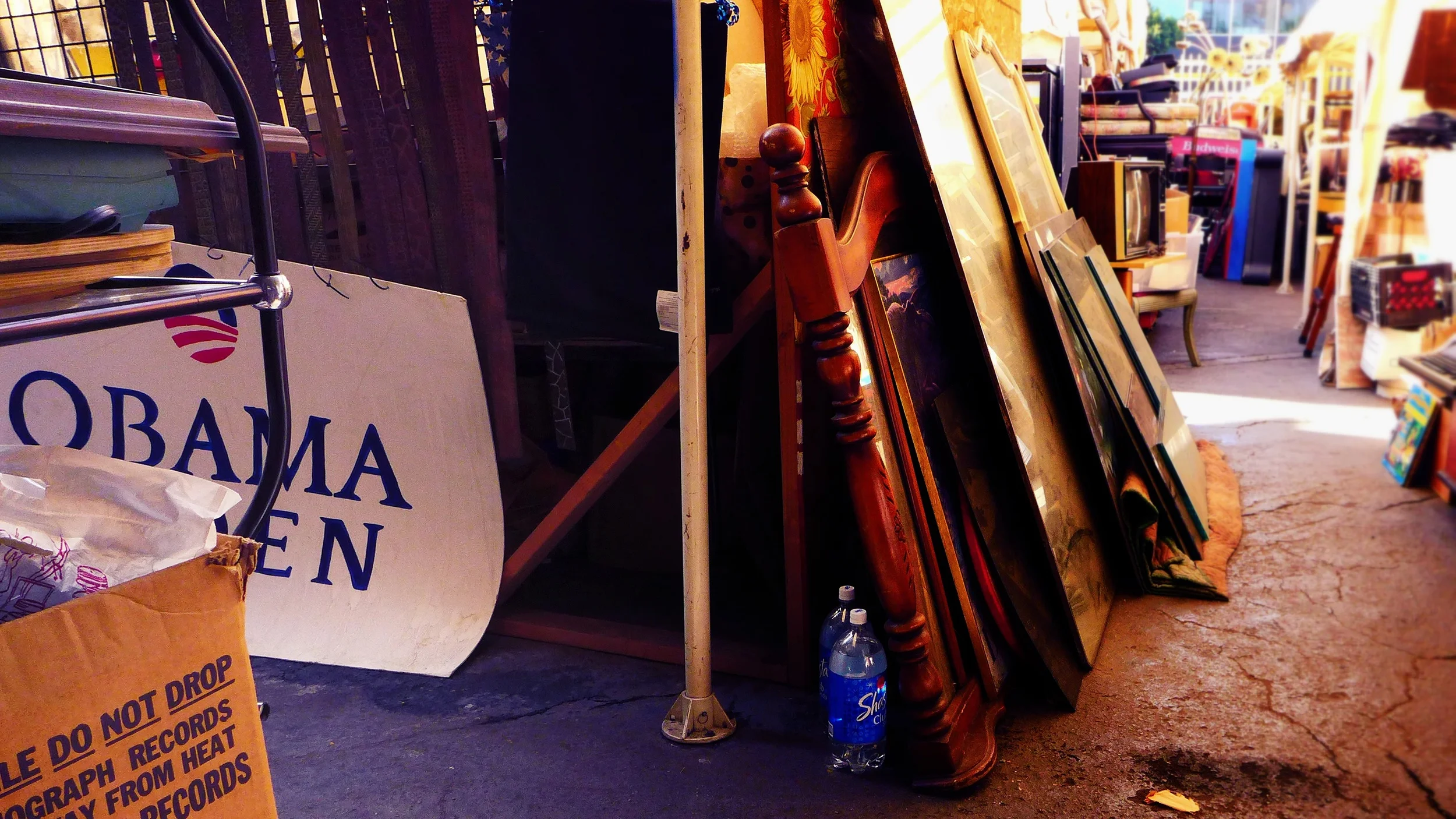 Rows of old furniture including framed pictures and chairs at an outdoor flea market or garage sale.