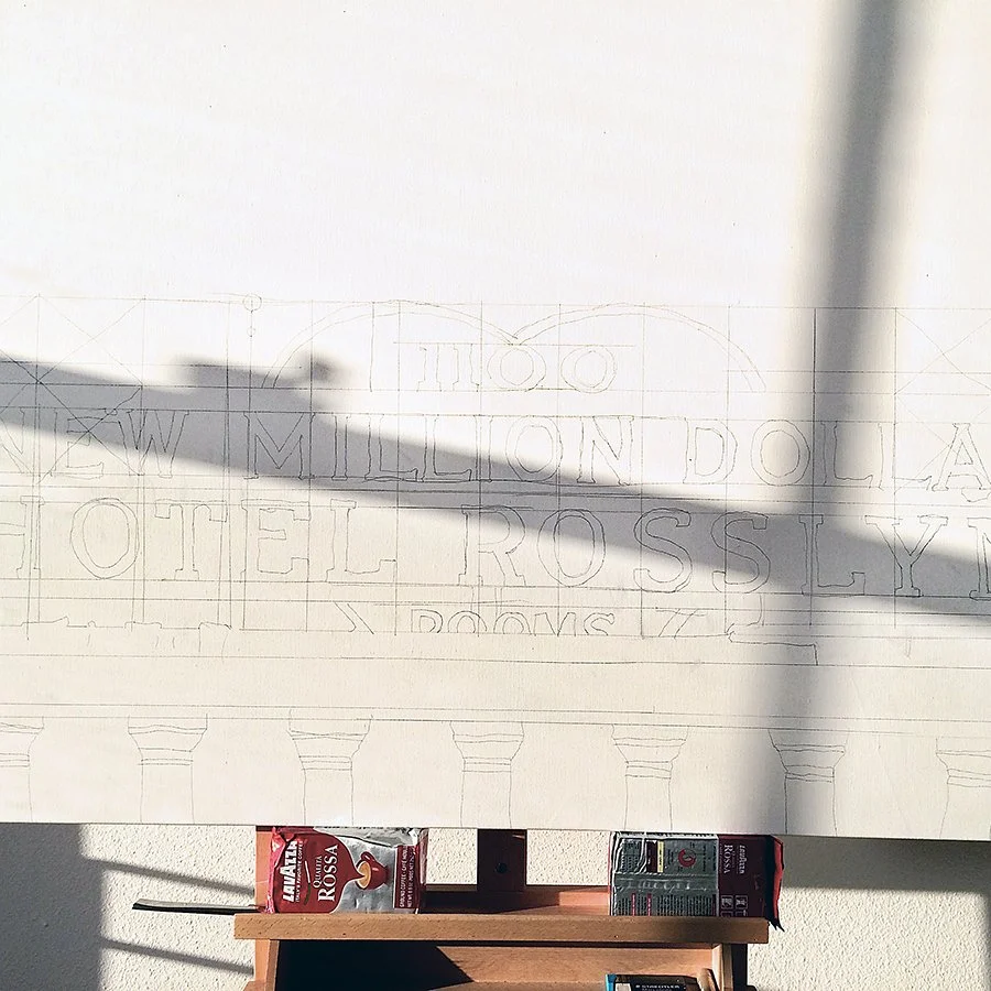 Sketch of a building with columns, featuring text that reads 'ONE MILLION DOLLARS HOTEL ROSSLY,' with shadows cast over the drawing, and some snack bags visible below.