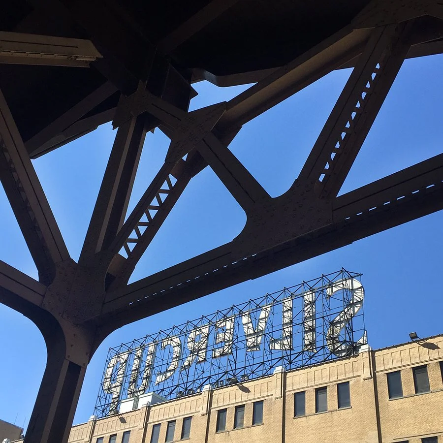 Looking up at a bridge structure with a clear blue sky and a building with a large sign reading "DIXONYKA" in the background.