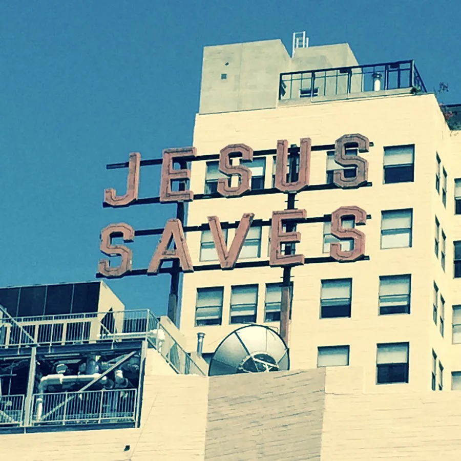 A large sign on a building that says 'Jesus Saves' in big letters.