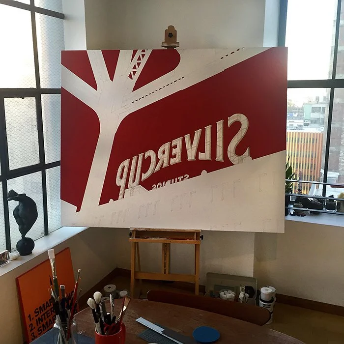 An easel with a large sign that has the word "Silvercup" in large letters and a red and white tree design, placed in a bright room with large windows.