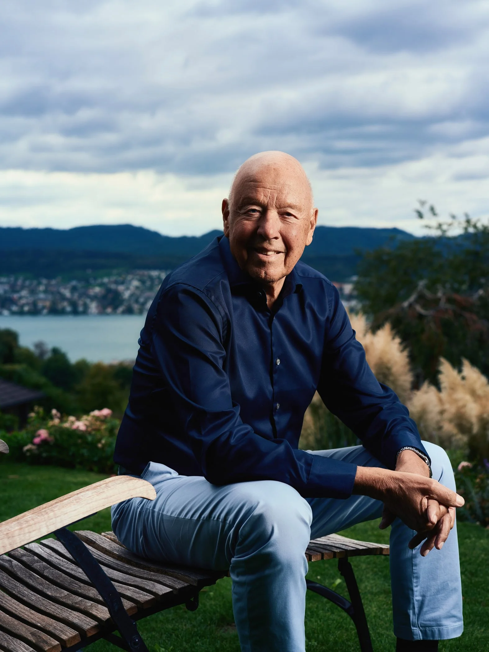 Portrait von Theo Müller auf einer Gartenbank vor dem Zürichsee.