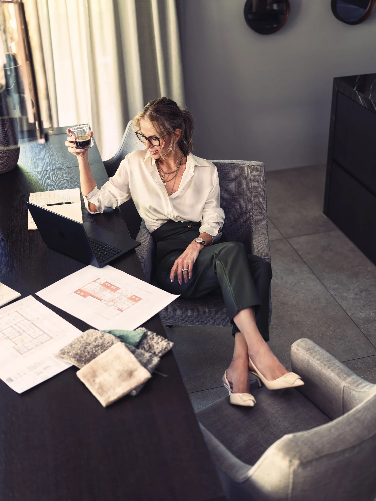 Personal Branding Fotografie einer Interior Designerin in Zürich bei der Arbeit mit Laptop, Plänen und Materialien