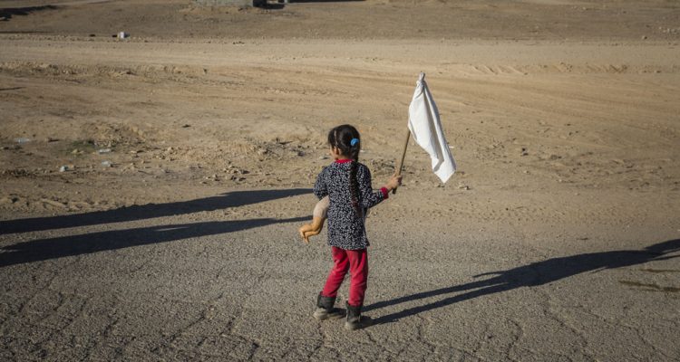 A young girl carrying a teddy bear and waving a white flag, heads towards an army outpost in the Samah neighbourhood on the eastern outskirts of Mosul, away from the heavy fighting engulfing the city. Photo: UNHCR/Ivor Prickett