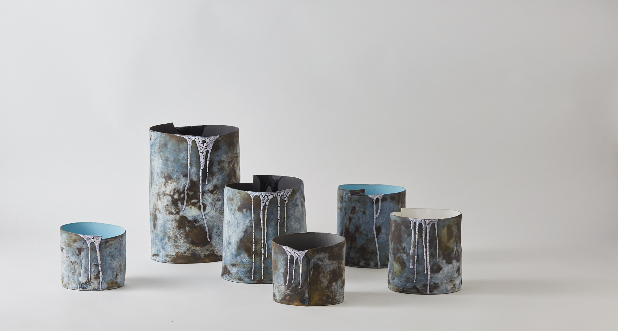 Your current work is inspired by your visits to Iceland. Can you tell us more about your process of translating the inspiration into ceramics? My first visit to Iceland in the summer of 2016 was just a holiday, but once home I couldn’t get the stunning, otherworldly landscape out of my head - petrified lava fields, austere horizons of black volcanic rock, snowy white peaks, steaming geothermal pools and icebergs on a glacial lagoon that create constantly shifting scenes. I was working on another project at the time, but photos from the trip were pinned up in my studio and unexpectedly ideas emerged, seeping into my work until there came a point when I decided to change my focus completely to the strangely addictive beauty of this ancient land. My making has always been an impressionistic response to place and experience, and Iceland’s monochromatic landscape seemed a natural fit with my work. Some pieces have become more sculptural with undulating walls and rims that mimic the outline of patches of snow in my photographs, a reflection of receding glaciers and a reference to climate change so clearly evident in the topography of the Icelandic landscape. Take a horizontal cross section of the many stunning waterfalls and careful observation sees this shape repeated. The colour palette reflects Iceland’s hues, mainly black, greys, whites, and blues. The painterly exterior and dribbled crackle glaze reference waterfalls and landscape.